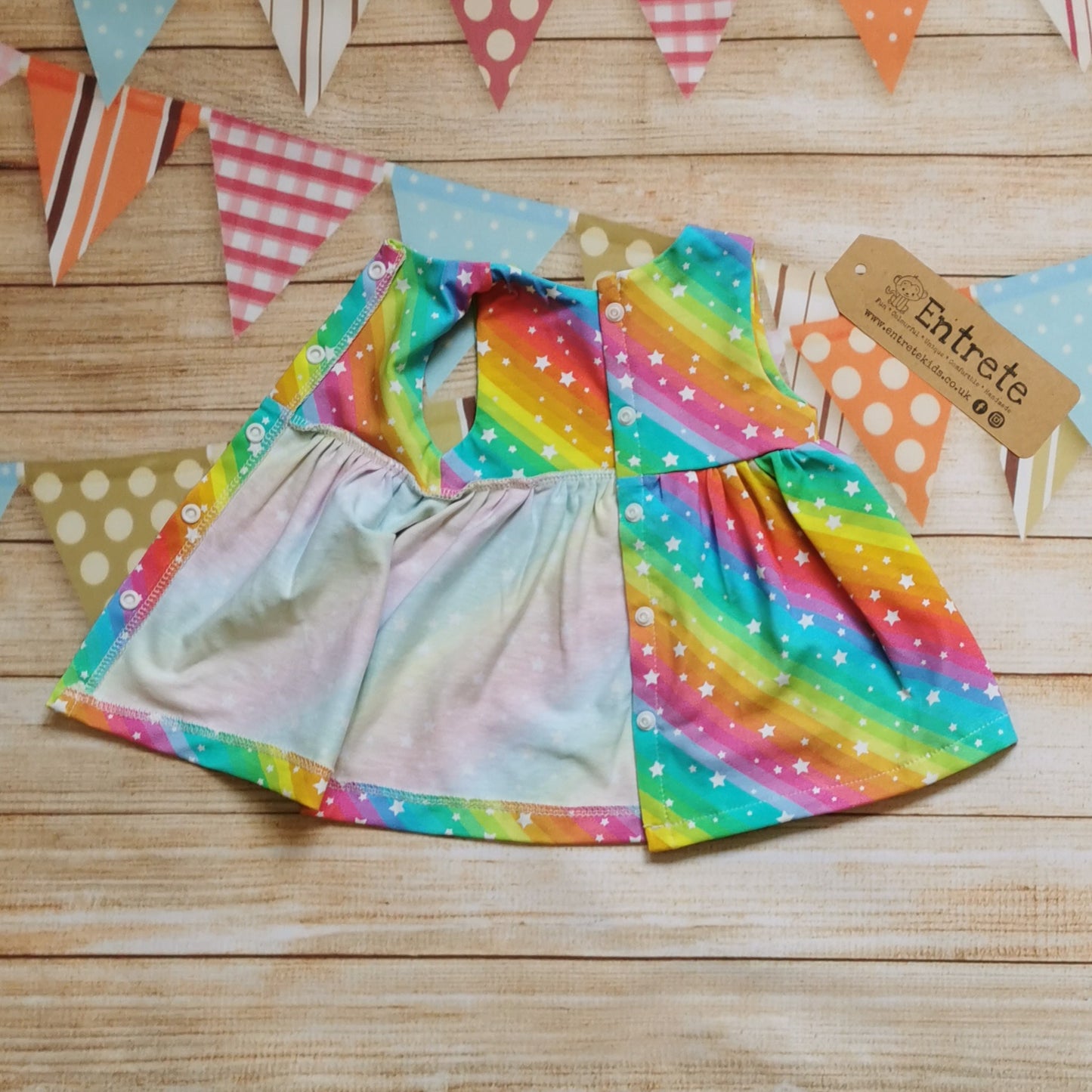 Girls & Babies back popper dress, handmade in bright rainbow stars cotton jersey. Shown with babies full length popper opening.