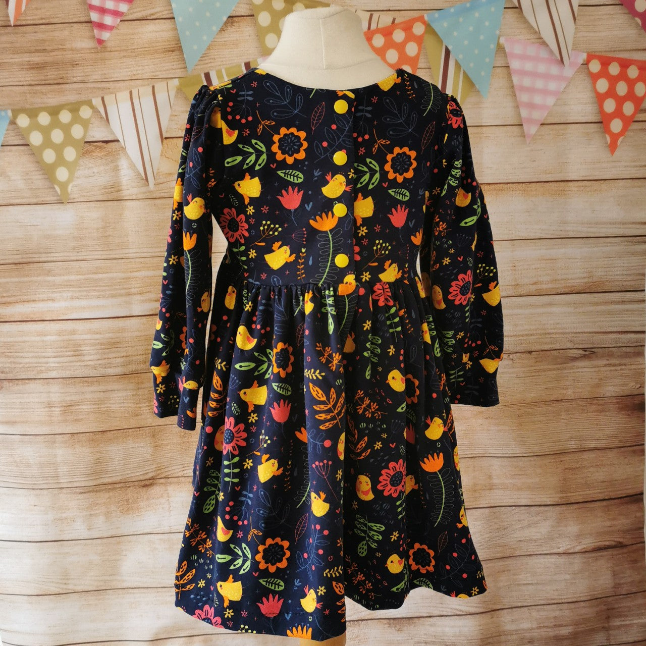 Long Sleeved girls back popper dress, handmade from the cute navy chicks cotton jersey. Showing the back popper entry down to the waist, as used on sizes 9-12 months and above.