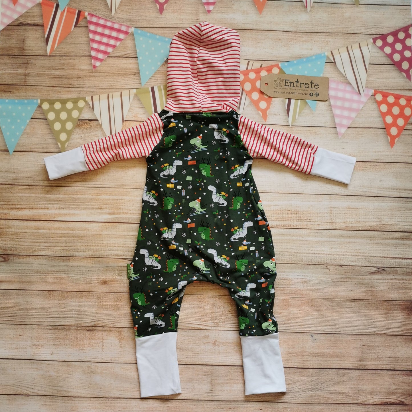 Rear of the roarsome Christmas dinosaurs hooded popper romper. Handmade using dark green festasaurus, red striped and white cotton jerseys. Perfect for the dinosaur fanatic in your life!