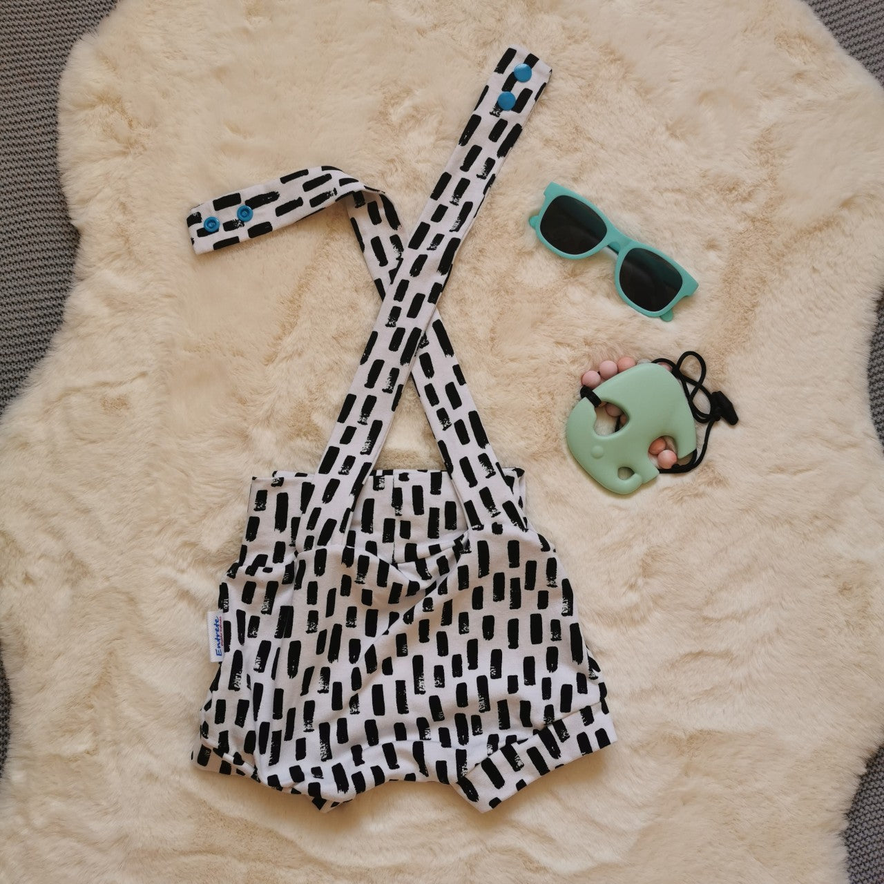 Rear view of light and airy girls cross strap dungaree shorts, with shoulder popper entry. Handmade using monochrome abstract stripes cotton jersey.