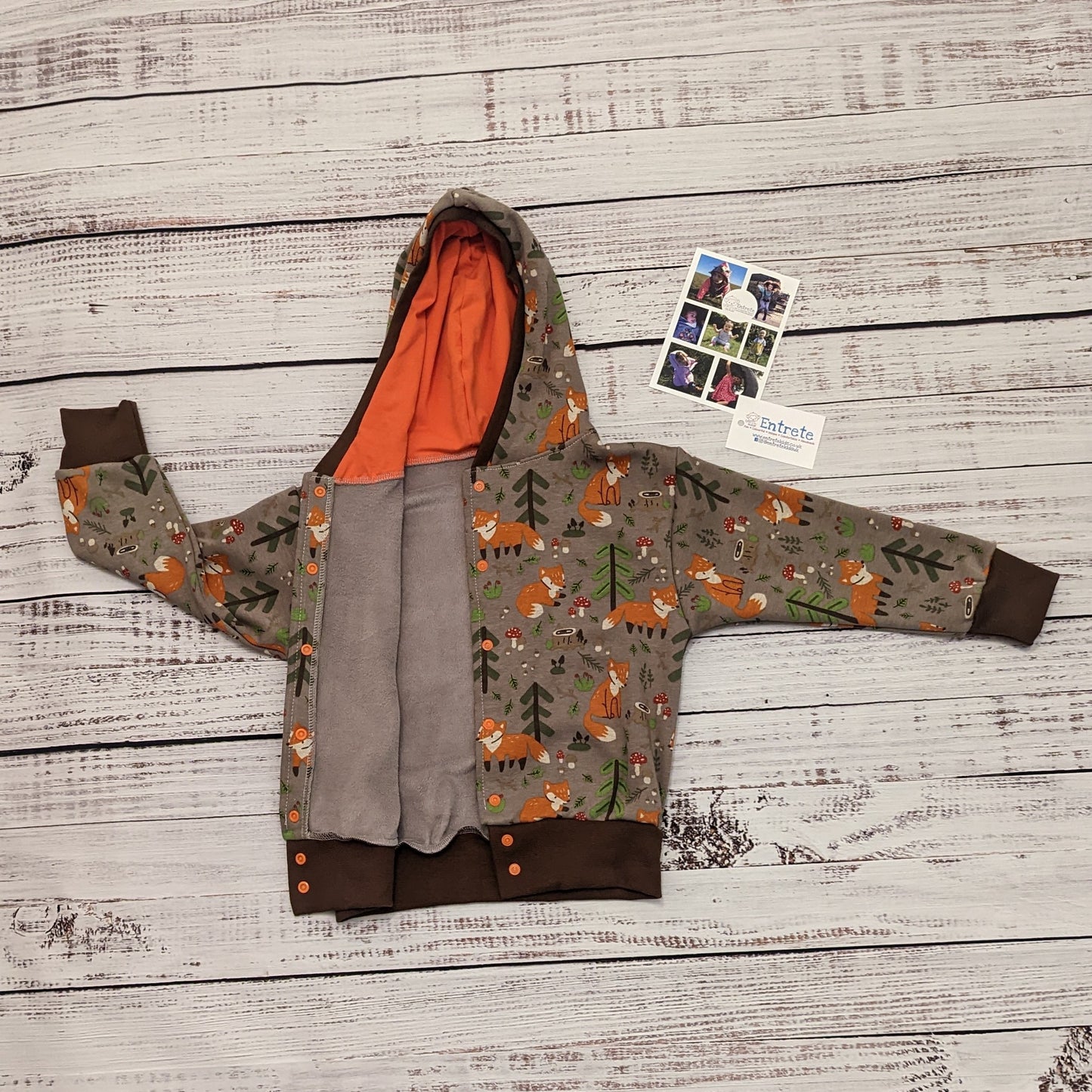 The sumptuously soft forest foxes popper hoodie. Handmade using forest foxes alpine fleece, chocolate cotton ribbing and orange cotton jersey. Shown with front popper entry open.