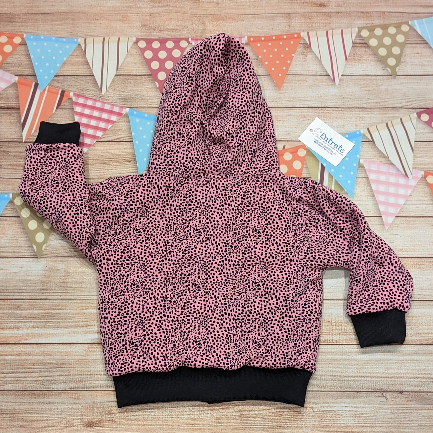 The reversible cat hoodie featuring fun tail and ear detailing. Handmade using grey polar fleece, light grey cotton french terry, black organic cotton jersey and graphite ribbing. The reverse is made using pink cheetah print cotton jersey. This cat hoodie is so unique and is great for imaginative play. Showing the rear of the reverse side.