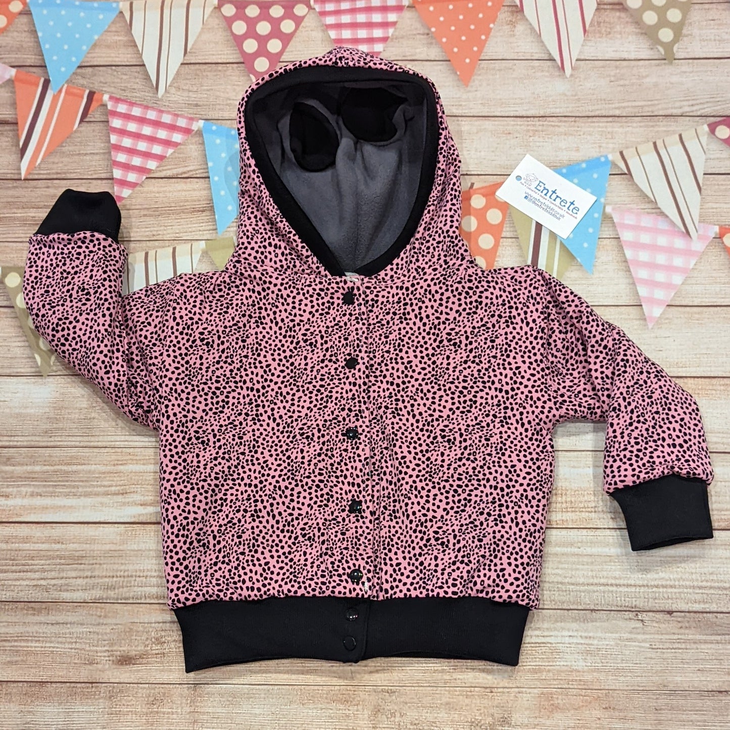 The reversible cat hoodie featuring fun tail and ear detailing. Handmade using grey polar fleece, light grey cotton french terry, black organic cotton jersey and graphite ribbing. The reverse is made using pink cheetah print cotton jersey. This cat hoodie is so unique and is great for imaginative play. Shown on the pink cheetah print reverse.