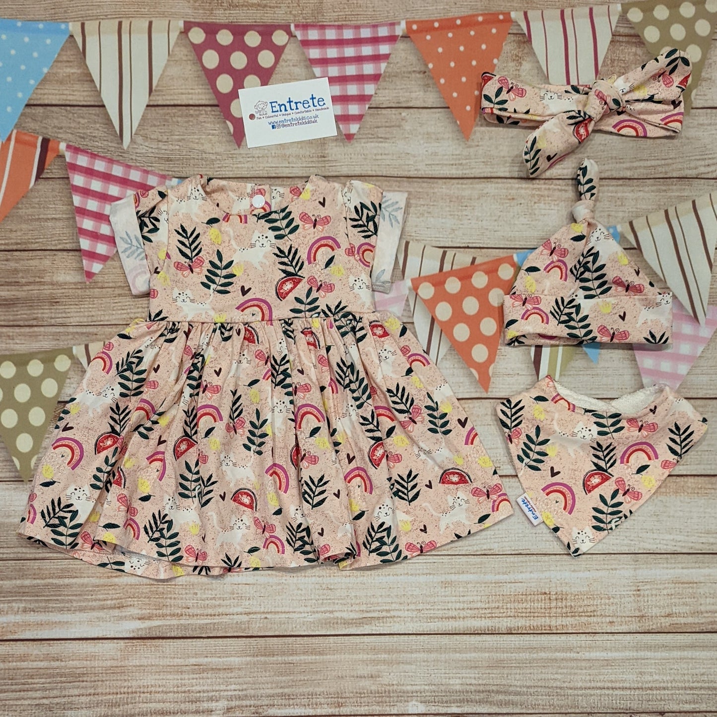 The playful pink cats girls dress, handmade using pink cats cotton jersey. Short sleeve version shown with matching headband, tie top hat and bamboo bib..
