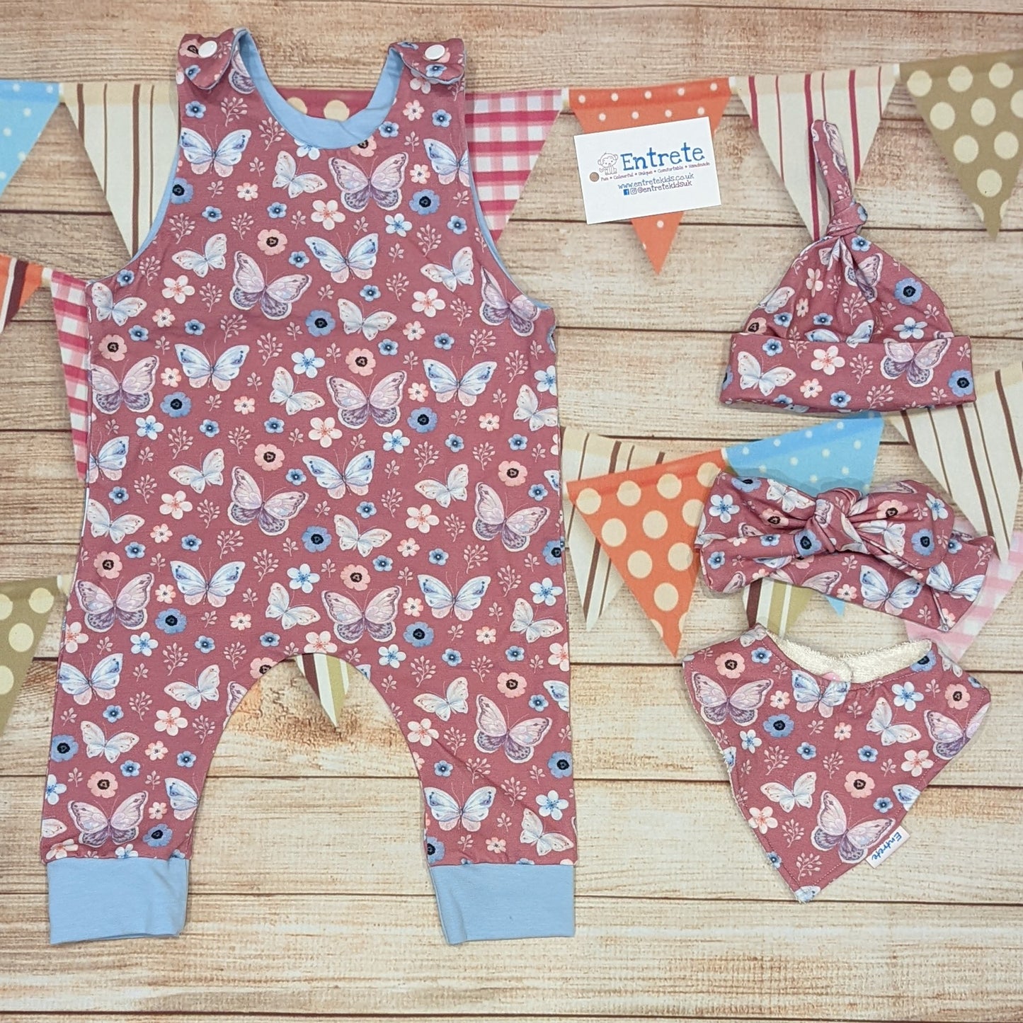 Pretty pink butterflies on contrasting sky blue sleeveless romper. Handmade using organic pink butterflies cotton jersey and sky blue cotton jersey. Shown with matching tie top hat, headband and bamboo bib.
