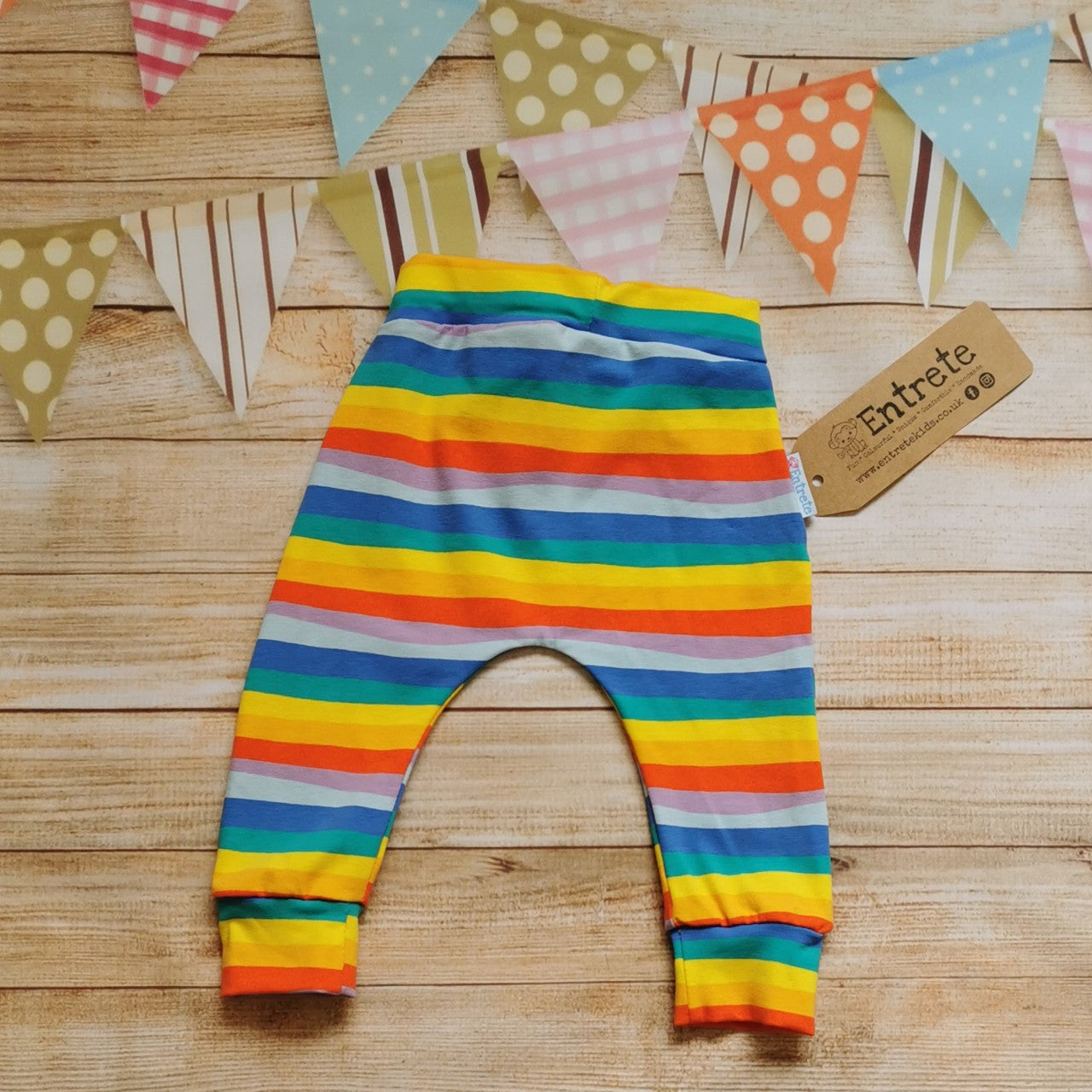 Rear view of harem joggers with elasticated waist, dropped crotch and roll-able ankle cuffs. Handmade in colourful red rainbow striped cotton jersey.