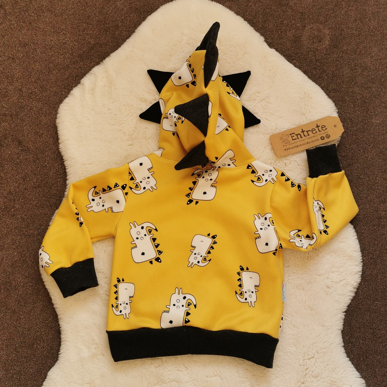 The adorable and fun mustard Dinosaur hoodie. With teeth and spines on the hood and a contrasting front pocket. Handmade using mustard dinosaurs cotton sweatshirt fleece, black cotton jersey and graphite cotton ribbing. From the rear.