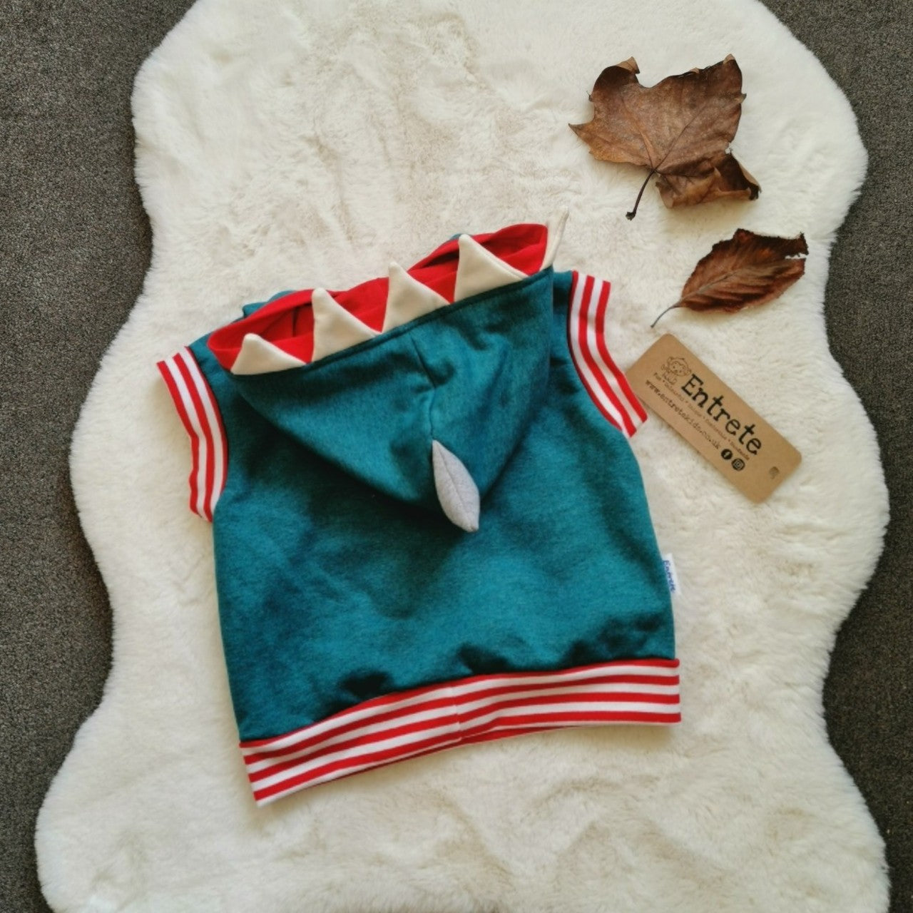 The fearsome teal shark hoodie. With sharks teeth and fin to the hood and a contrasting front pocket. Handmade using teal, white and grey cotton sweatshirt fleeces, red cotton jersey and red striped cotton ribbing. Shown from the rear.