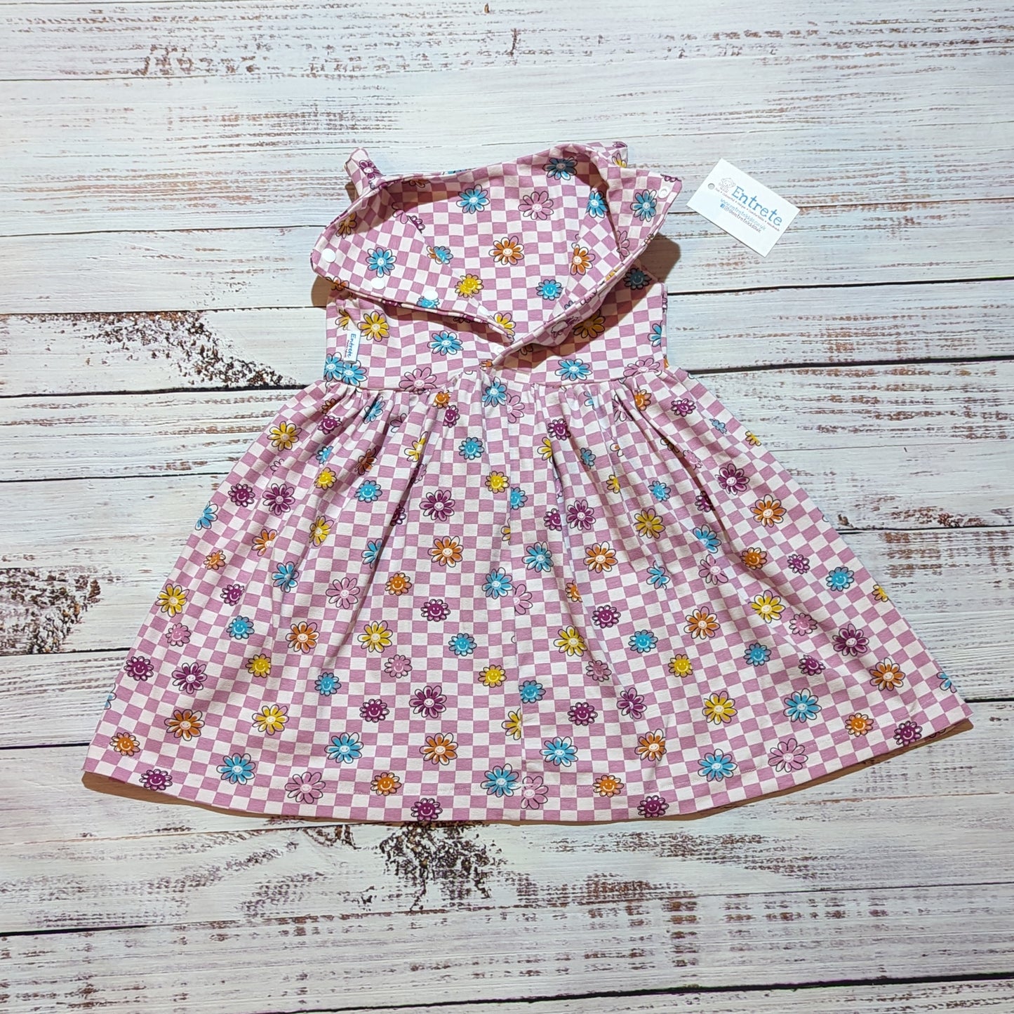 The adorable pink checked happy flowers dress. handmade in soft and comfy cotton jersey with a smiling flowers print. Shown with the back popper entry open.