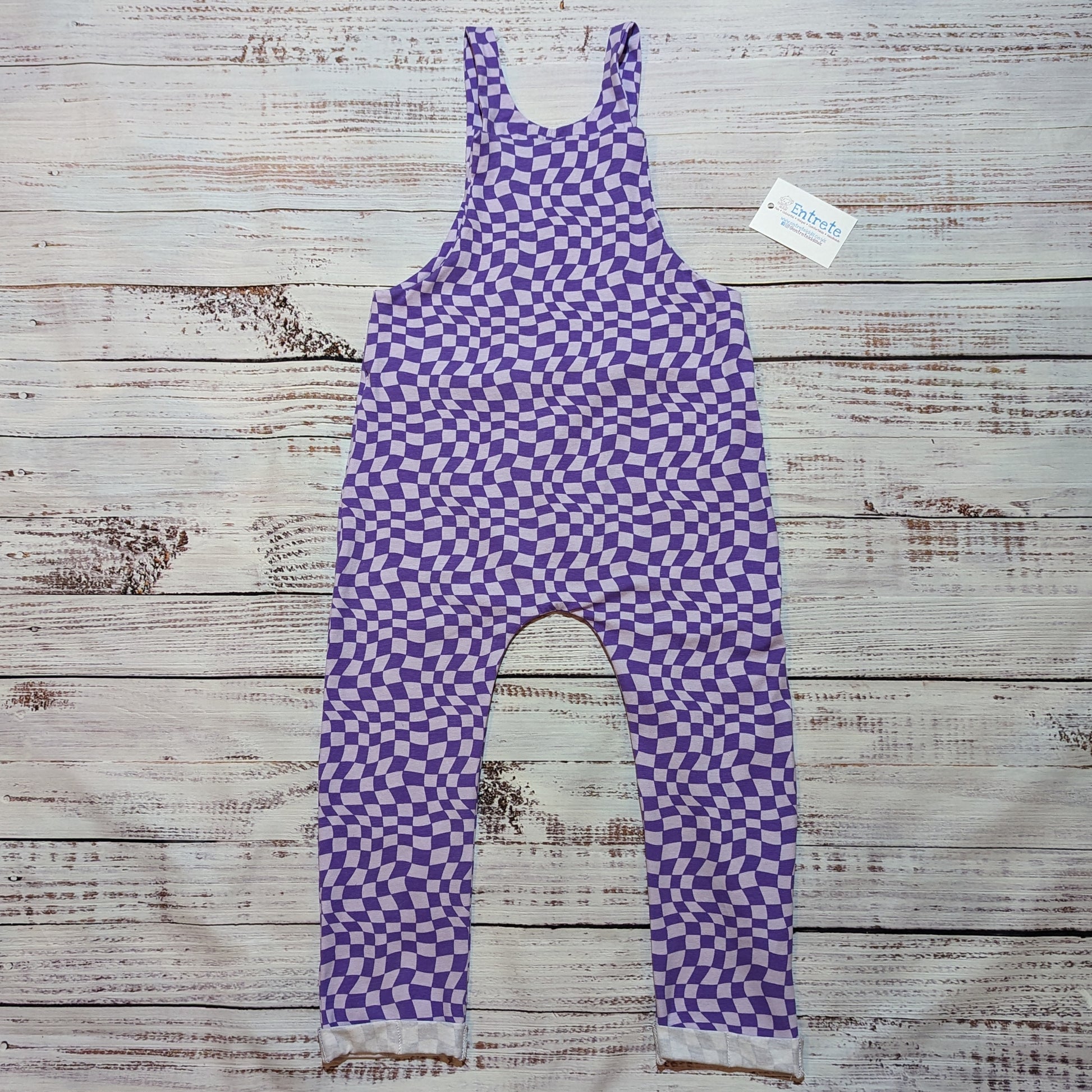 Kid's dungarees in a warped purple trippy checked print. Handmade in soft, stretchy and comfortable cotton jersey. Shown from the rear.