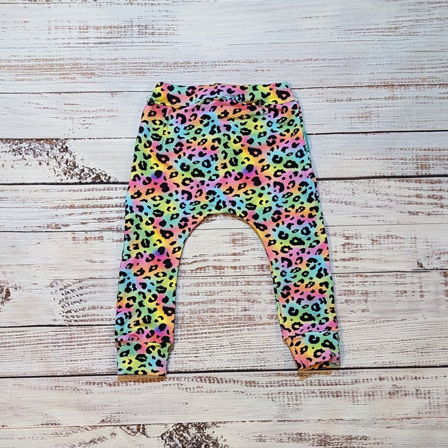 Child and toddler colourful animal print harem joggers. Lovingly handmade using soft and comfortable rainbow leopard print cotton jersey. Showed from the rear.