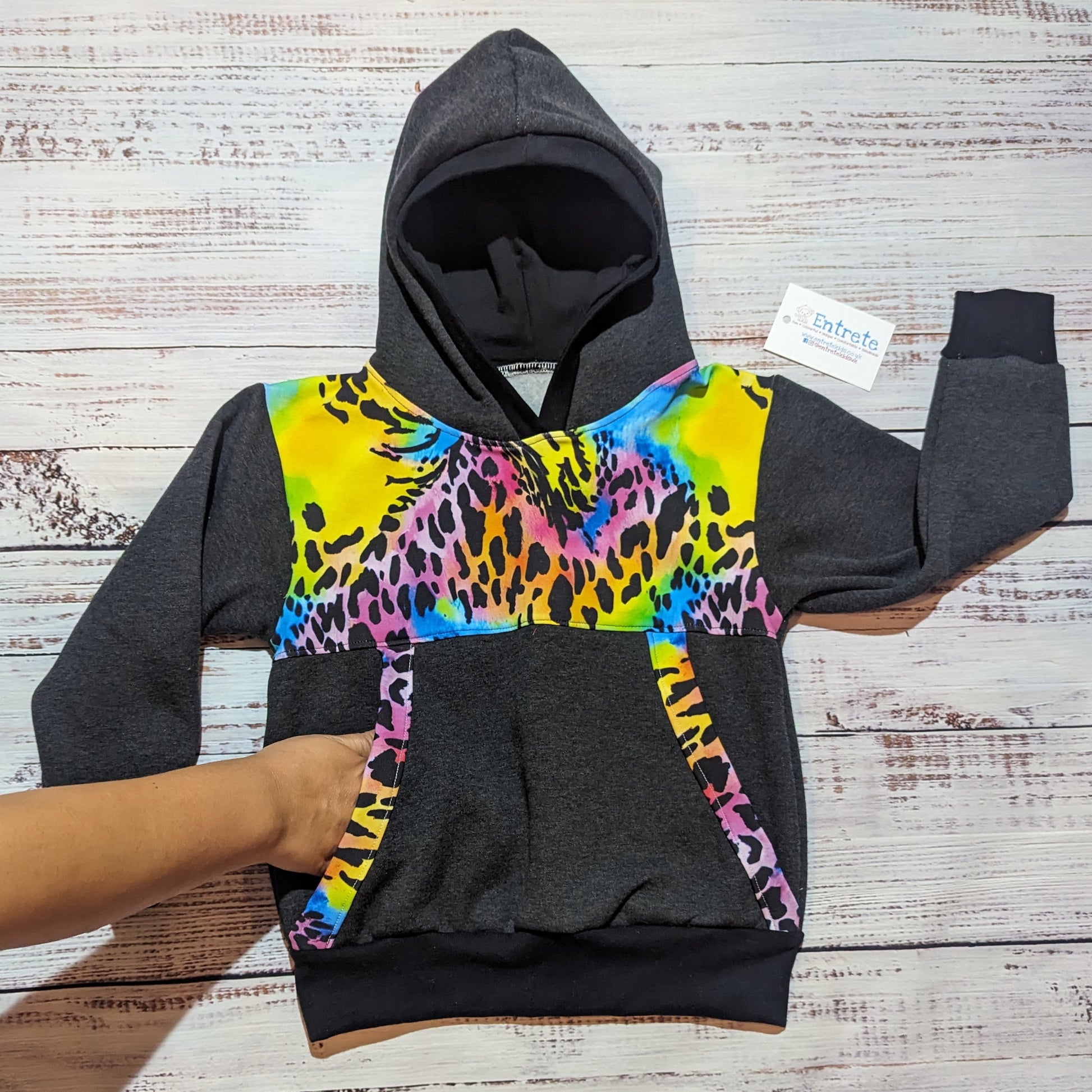 Demonstrating the front pocket of the vibrant neon animal print on charcoal adults hoodie.