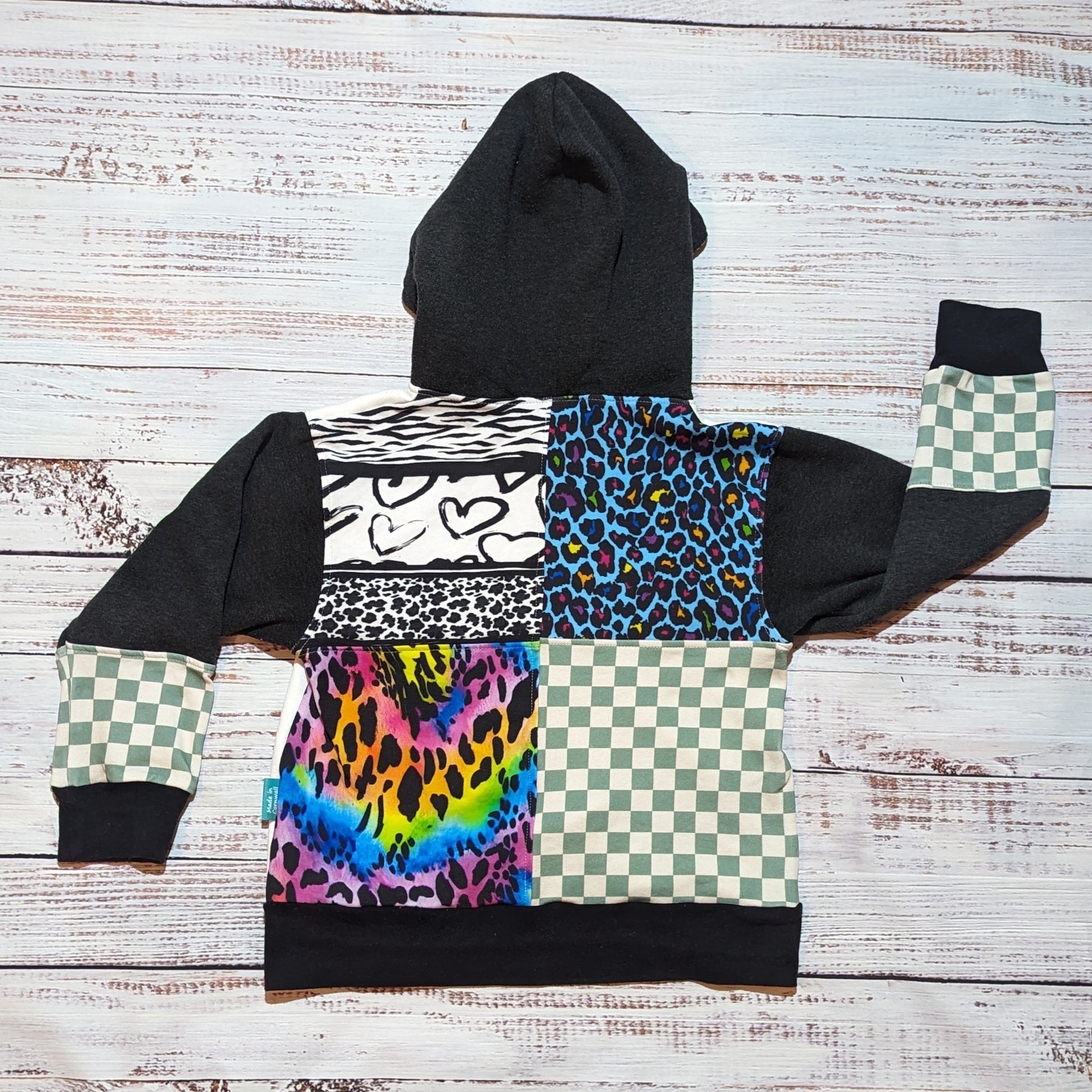 A stunning hoodie with an eclectic mix of colours and patterns. Handmade using neon animal print, neon leopard print, animal hearts, mint checked, white and charcoal cotton French terry and cotton ribbing. Showing the patchwork style back.
