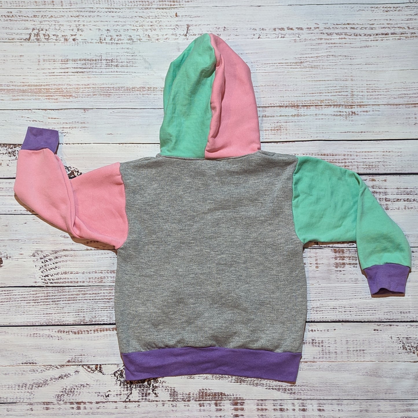 The fabulous purple trippy checked hoodie. Handmade using purple trippy checked cotton jersey, mint, pink and grey cotton French terry and purple cotton ribbing. Shown from the rear.