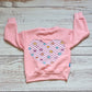 Pink checked happy flowers heart sweatshirt. Handmade in your colour choice of cotton French terry, with matching cotton ribbing and fun pink checked smiling flowers heart detailing on the back. Shown in pink French terry from the rear.