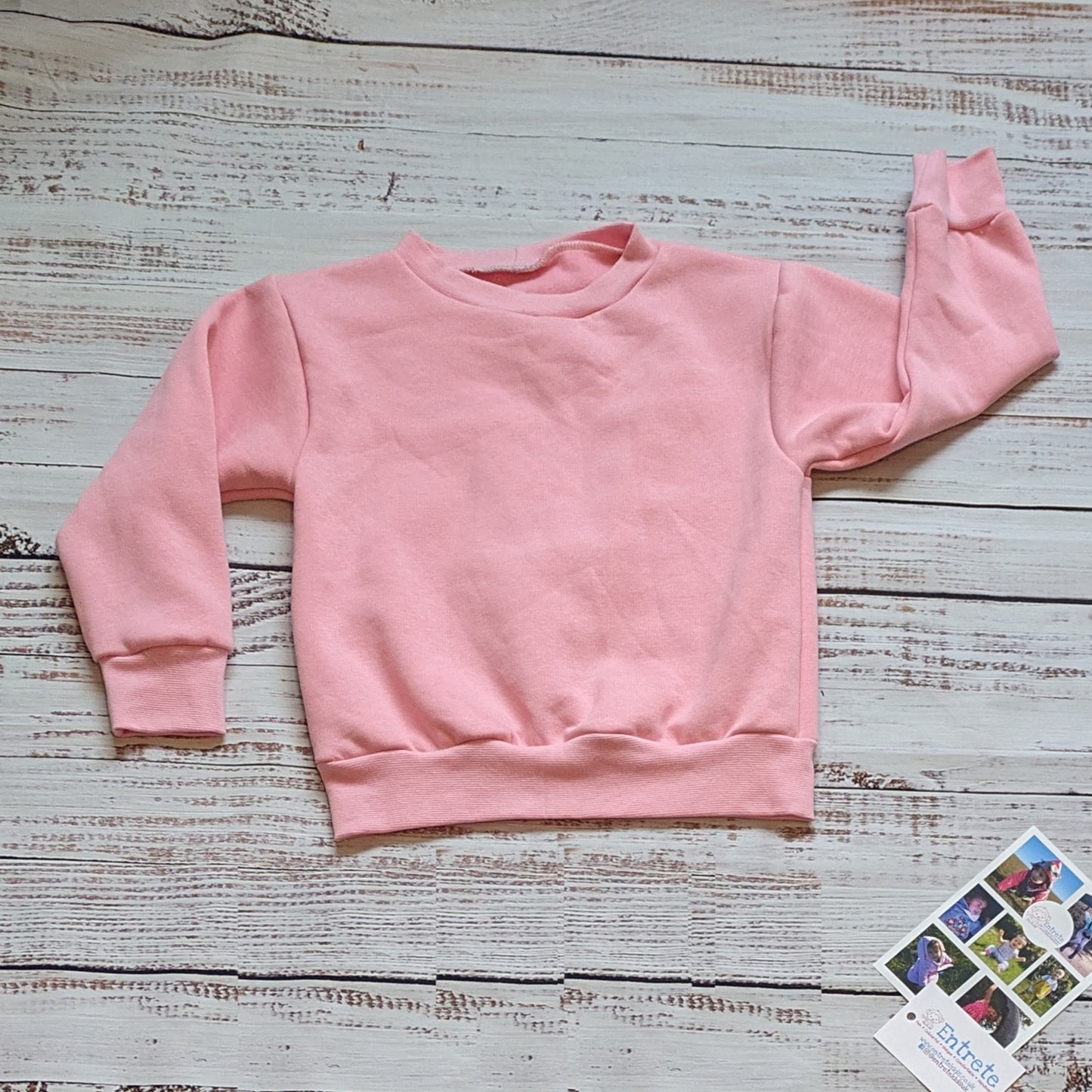 Pink checked happy flowers heart sweatshirt. Handmade in your colour choice of cotton French terry, with matching cotton ribbing and fun pink checked smiling flowers heart detailing on the back. Shown in pink French terry from the front.