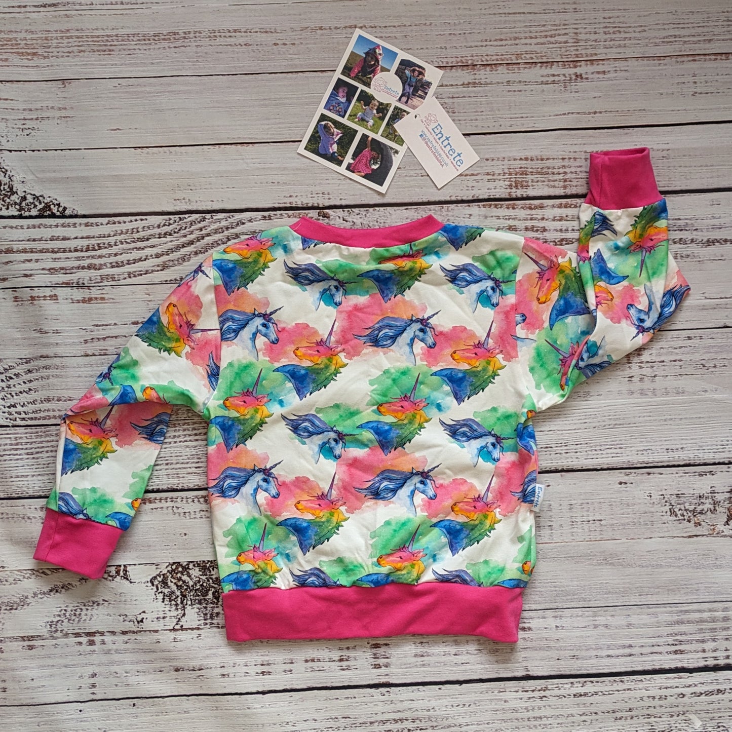 The lightweight, colourful unicorns sweatshirt. Handmade using colourful unicorns on white cotton jersey and fuchsia cotton ribbing. Shown from the rear.