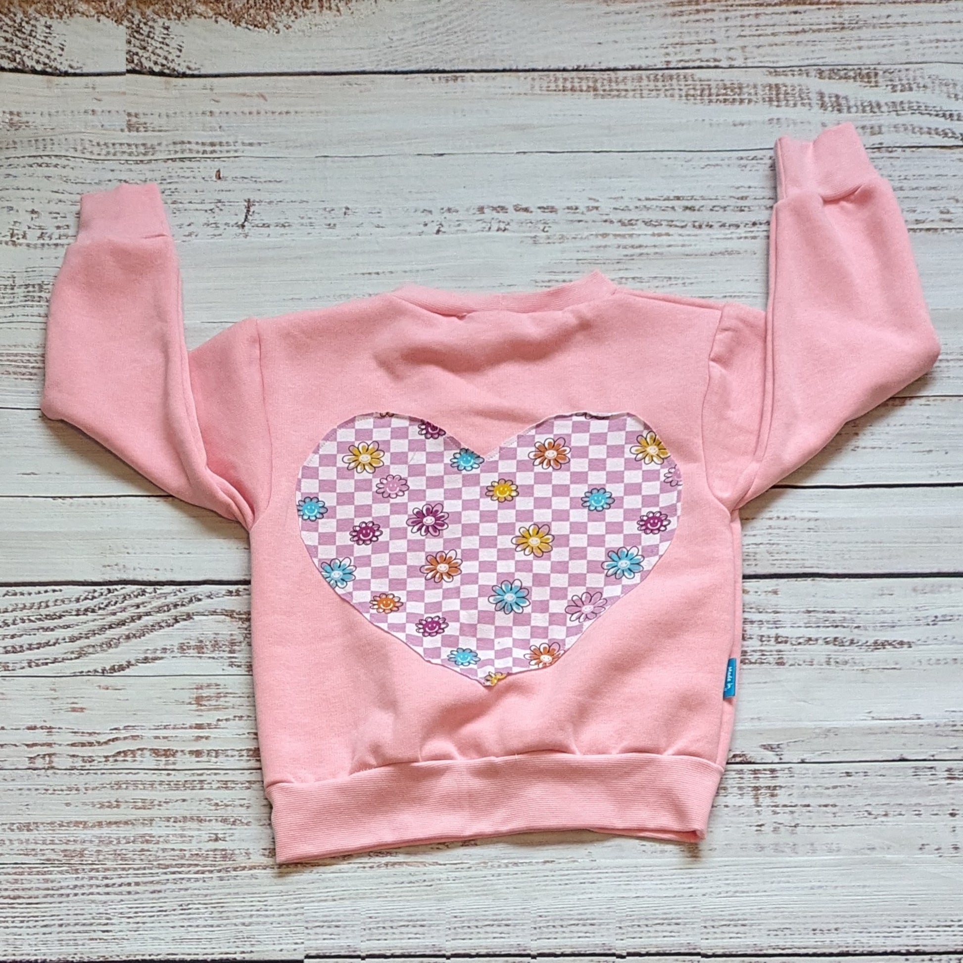 Rear view of the pink checked happy flowers heart sweatshirt. With a fun heart design on the back and choice of sweatshirt colour.