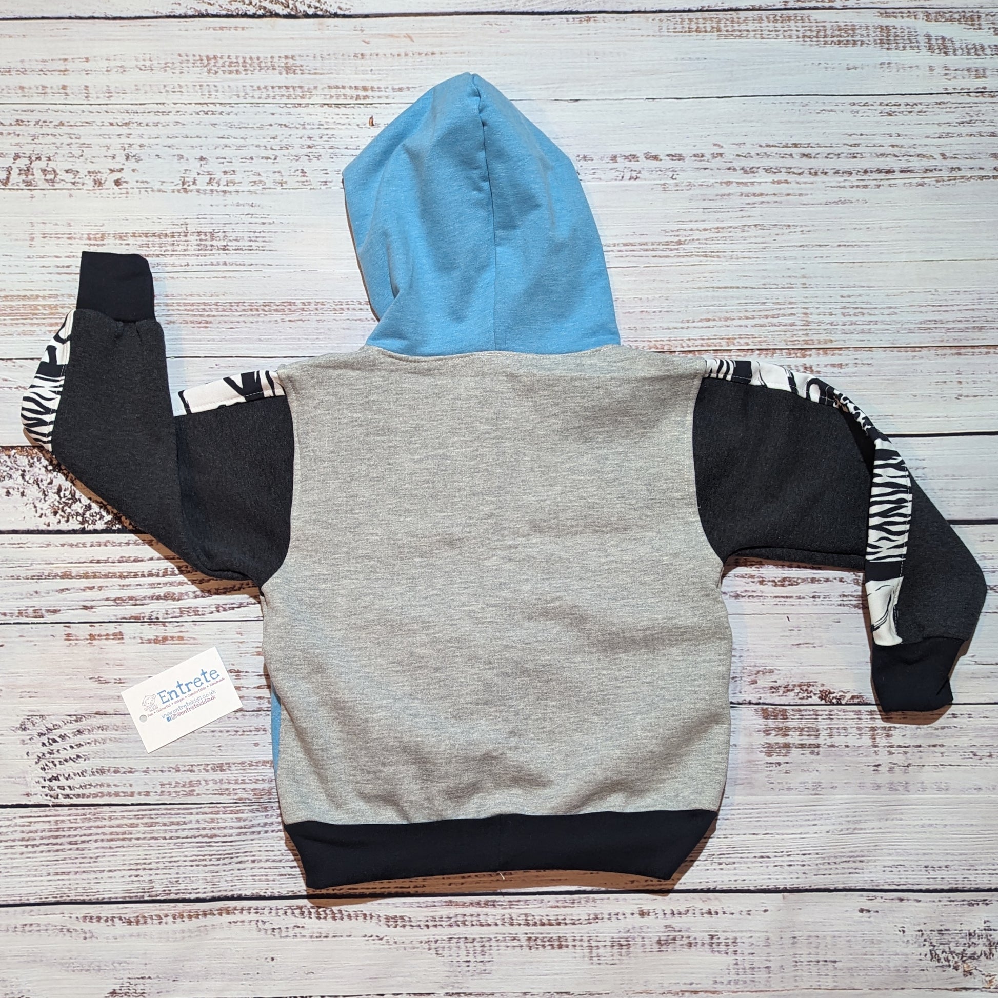 Sky blue, grey and animal hearts hoodie, with a zipped front pocket. Handmade using soft and comfortable cotton French terry. Shown from the rear.