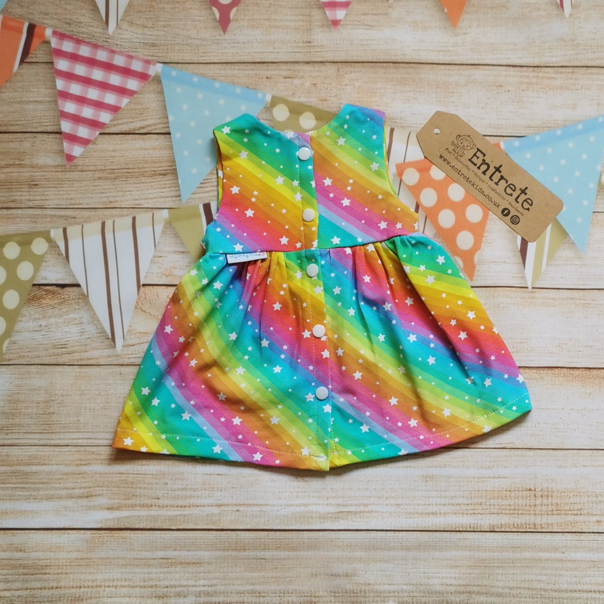 Rear of Girls & Babies back popper dress, handmade in bright rainbow stars cotton jersey. Shown in the sleeveless version.