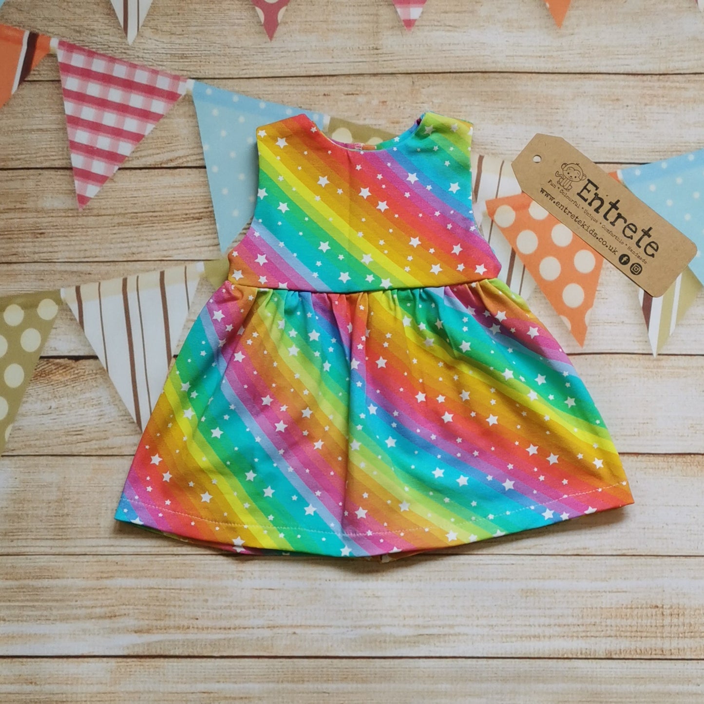 Front of Girls & Babies back popper dress, handmade in bright rainbow stars cotton jersey. Shown in the sleeveless version.