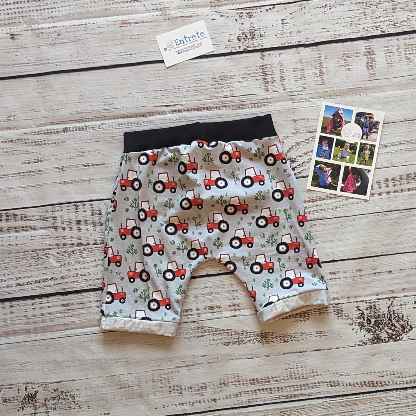 Fun red tractors on grey kids harem shorts. Handmade using grey tractors cotton jersey and black cotton ribbing. Shown from the rear.