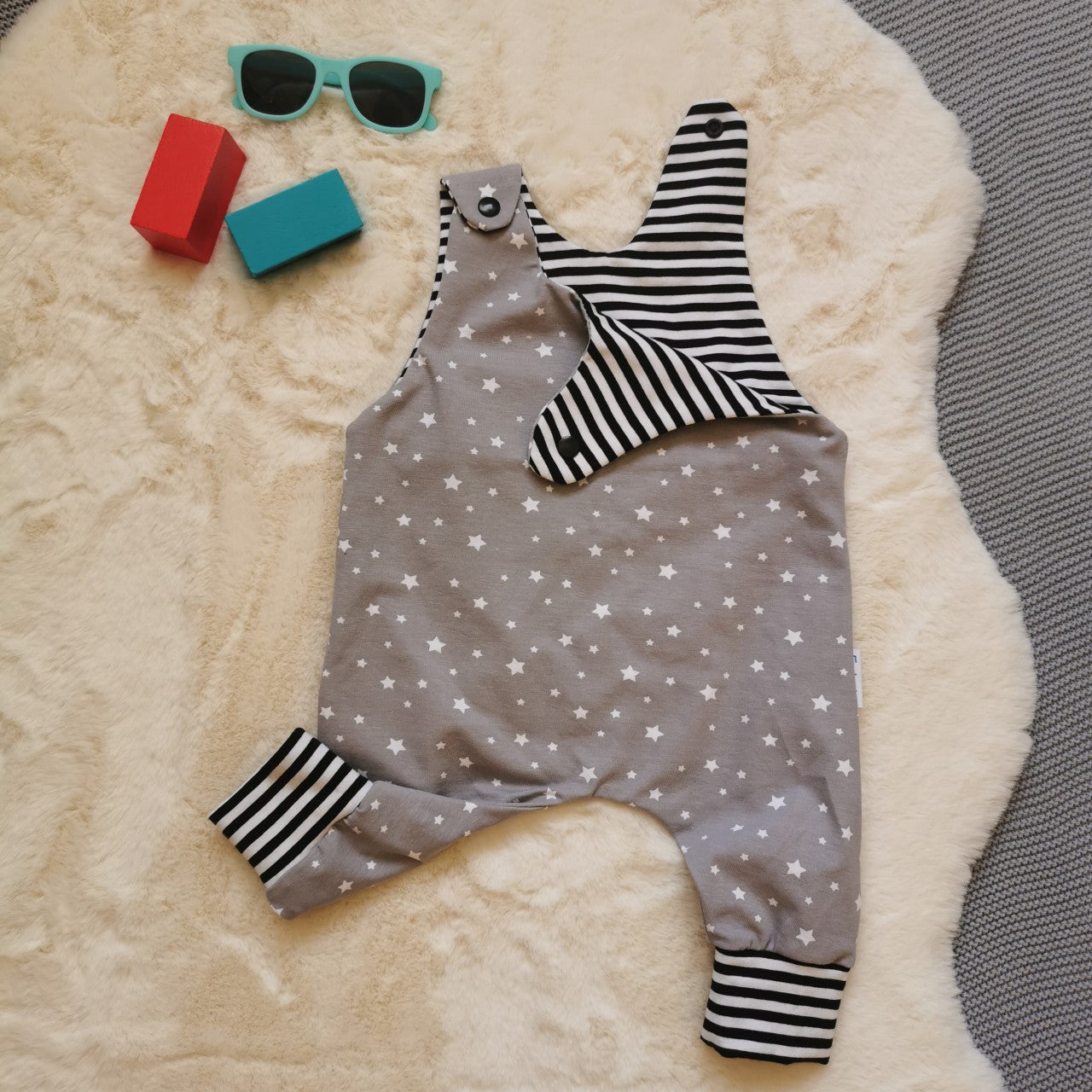 The dreamy grey stars sleeveless romper, soft and comfy with easy on shoulder popper entry. Handmade using grey stars and monochrome striped cotton jerseys'. Shown with one of the shoulder poppers open.