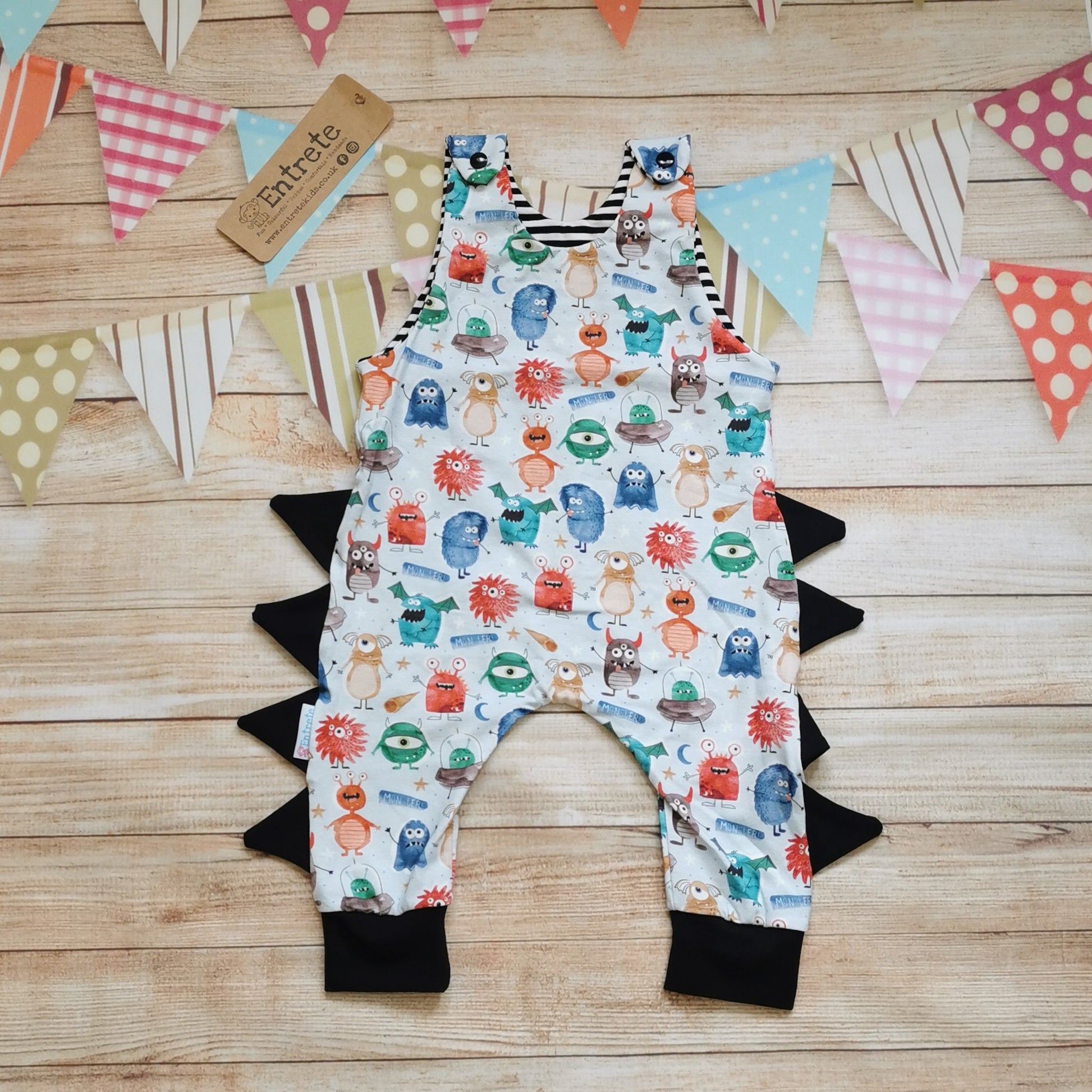 Front view of the insanely fun monster romper. Handmade from pale blue monsters cotton jersey, with black cotton jersey side detailing and cuffs and striped cotton jersey upper lining.