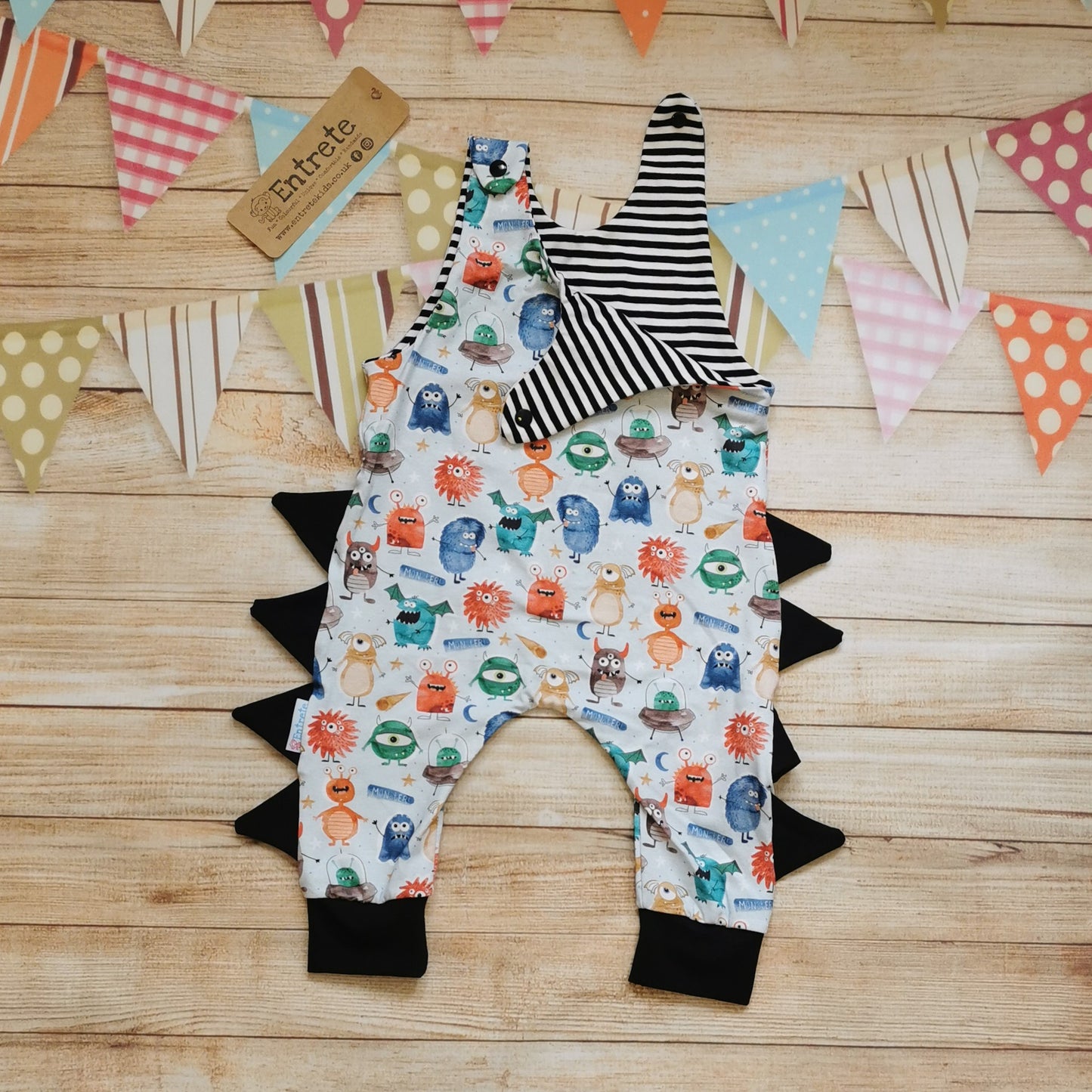 The insanely fun monster romper. Handmade from pale blue monsters cotton jersey, with black cotton jersey side detailing and cuffs and striped cotton jersey upper lining. Shown with one shoulder open revealing the striped upper lining.