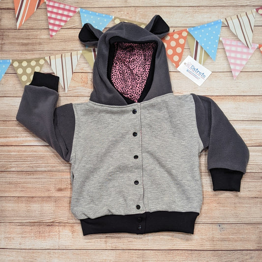 The reversible cat hoodie featuring fun tail and ear detailing. Handmade using grey polar fleece, light grey cotton french terry, black organic cotton jersey and graphite ribbing. The reverse is made using pink cheetah print cotton jersey. This cat hoodie is so unique and is great for imaginative play.