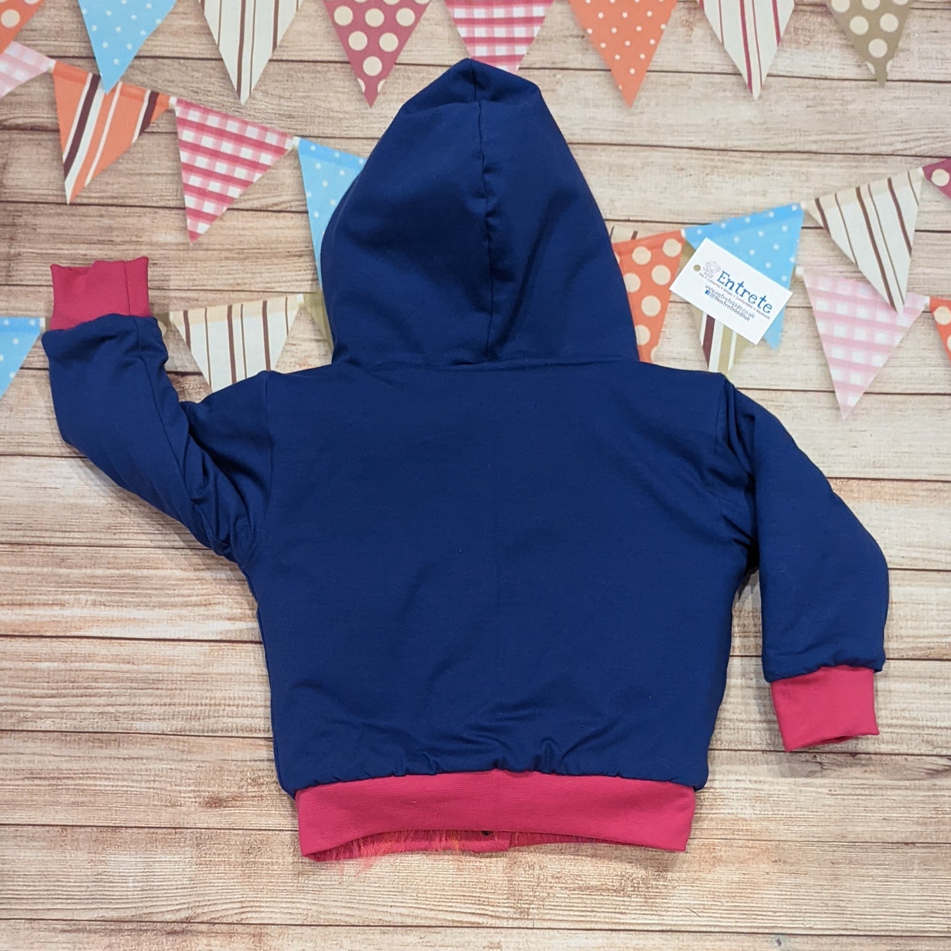 The colourful rainbow bear reversible hoodie. Handmade from rainbow long hair faux fur and fuchsia cotton ribbing, with royal blue cotton jersey on the reverse. Shown from the rear on the reverse side.