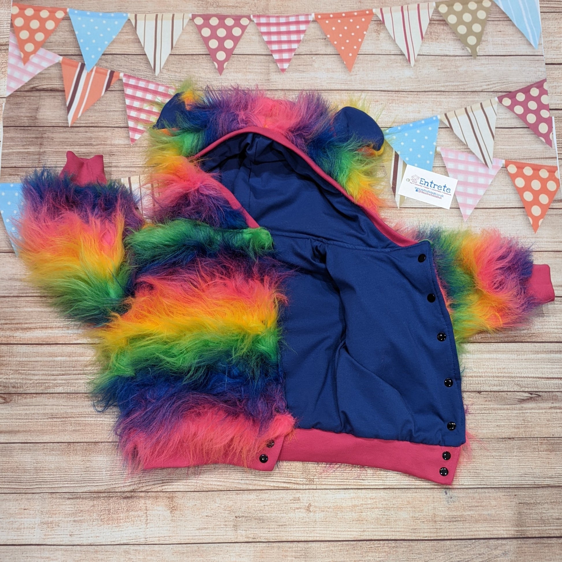 The colourful rainbow bear reversible hoodie. Handmade from rainbow long hair faux fur and fuchsia cotton ribbing, with royal blue cotton jersey on the reverse. Shown with popper entry open..