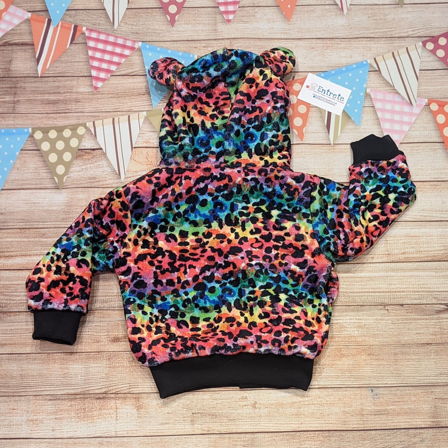 The colourful and warm rainbow leopard hoodie. Handmade using rainbow leopard print bubs fleece, black cotton ribbing, with a black cotton jersey reverse. Shown from the rear.