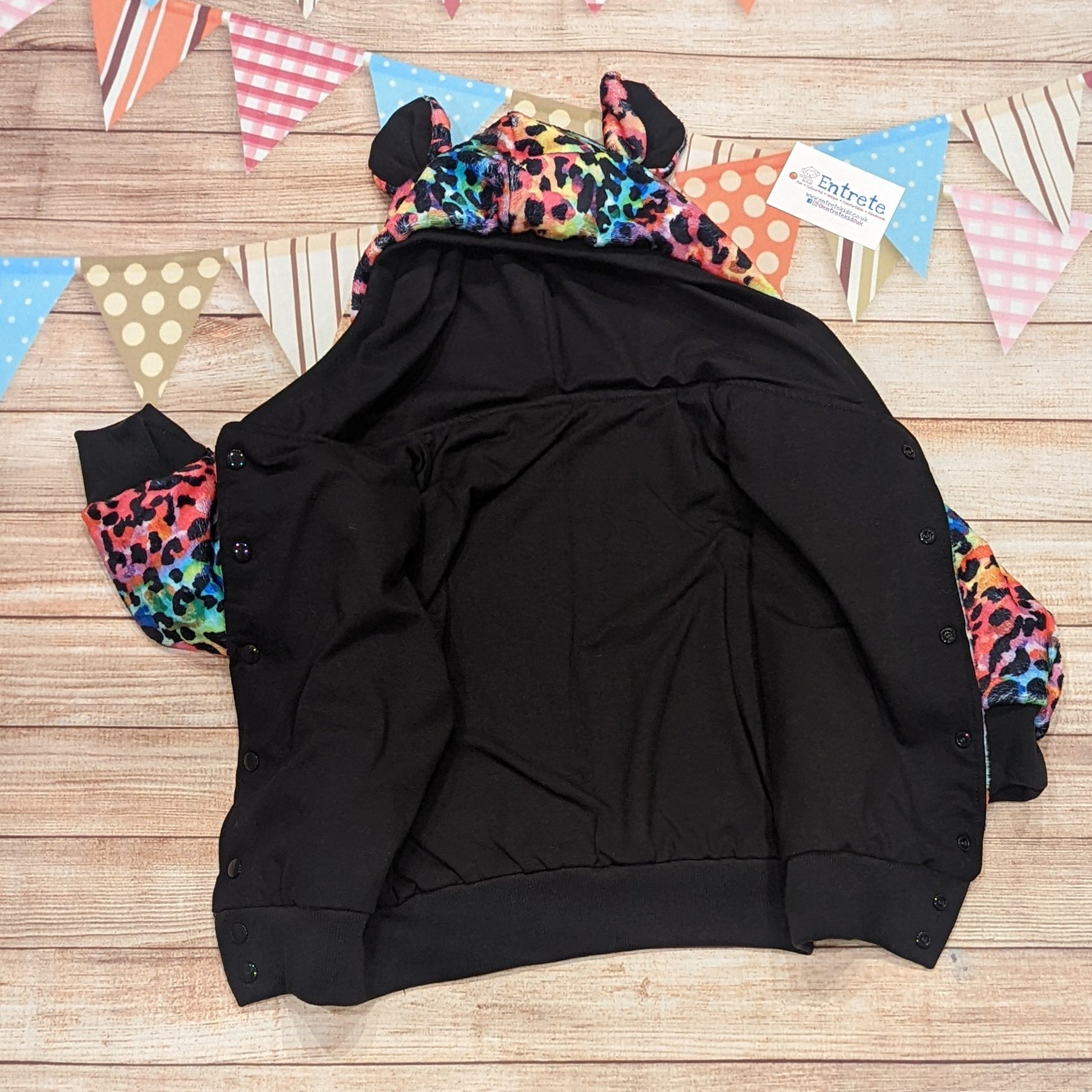 The colourful and warm rainbow leopard hoodie. Handmade using rainbow leopard print bubs fleece, black cotton ribbing, with a black cotton jersey reverse. Showing the black cotton jersey reverse.