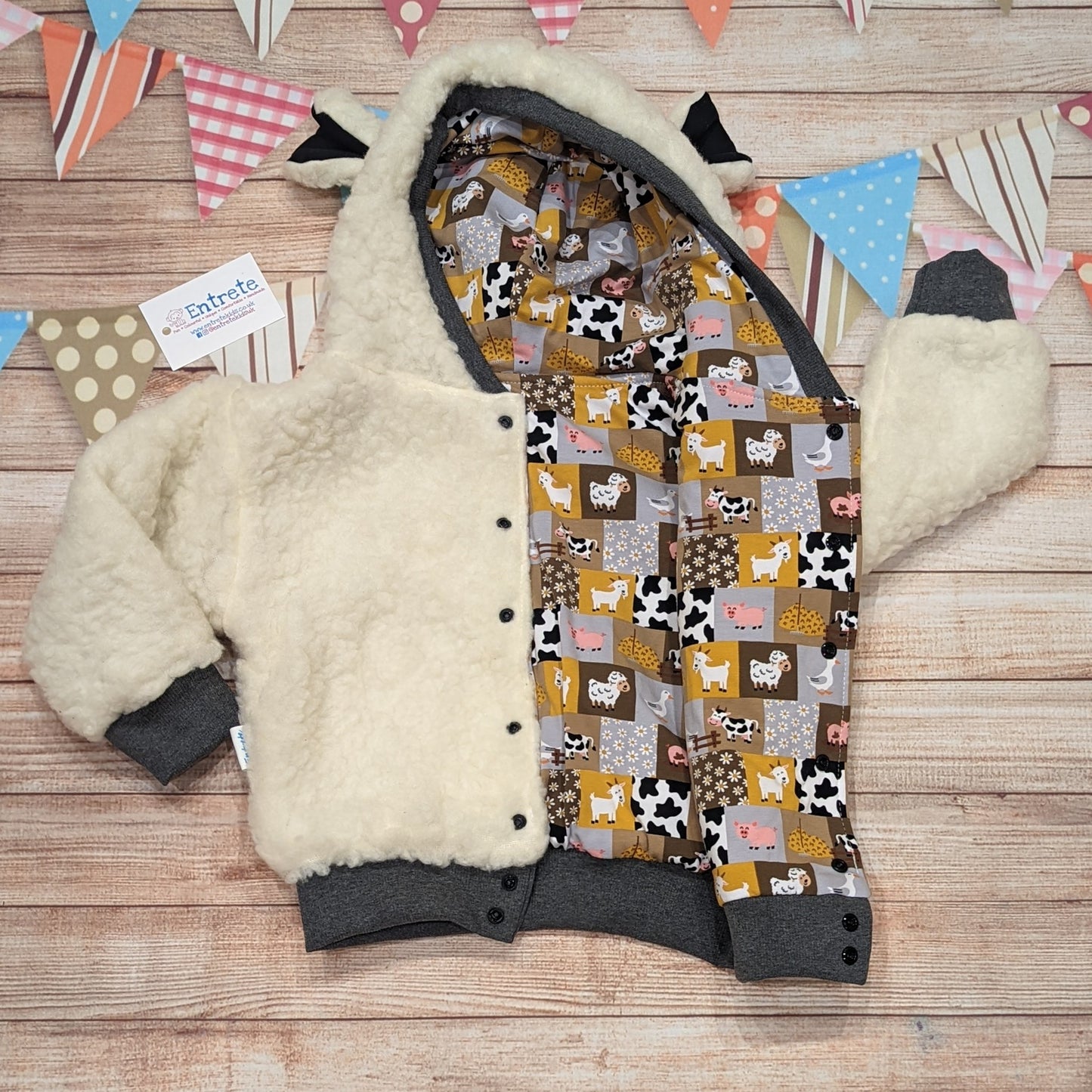 The adorable sheep hoodie handmade using sherpa fur and graphite cotton ribbing, with adorable and fun checkboard farm animals cotton jersey on the reverse. Shown with front popper entry open.
