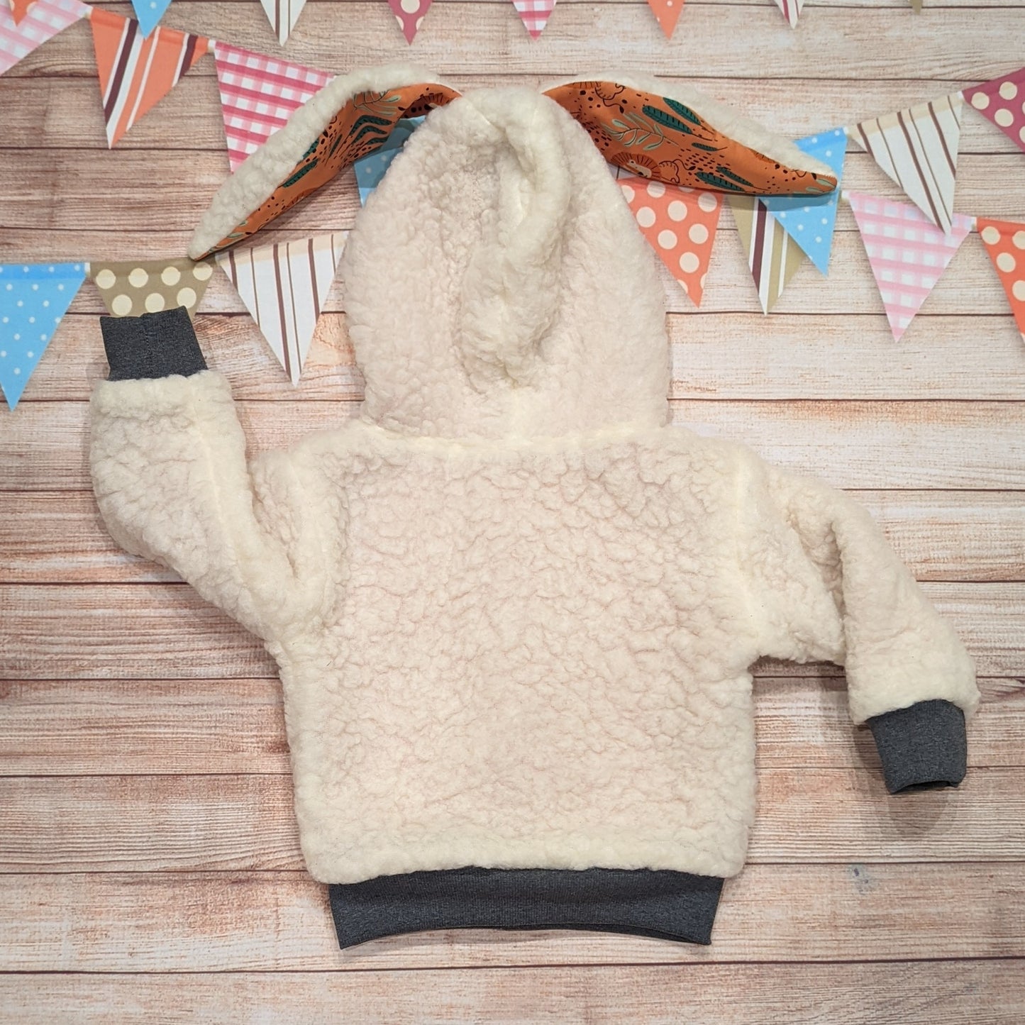 The gorgeous sherpa and orange lions reversible bunny hoodie. Handmade using sherpa fur, graphite ribbing and orange lions cotton French terry. Featuring front poppers and adorable bunny ears on the hood. Shown from the back.