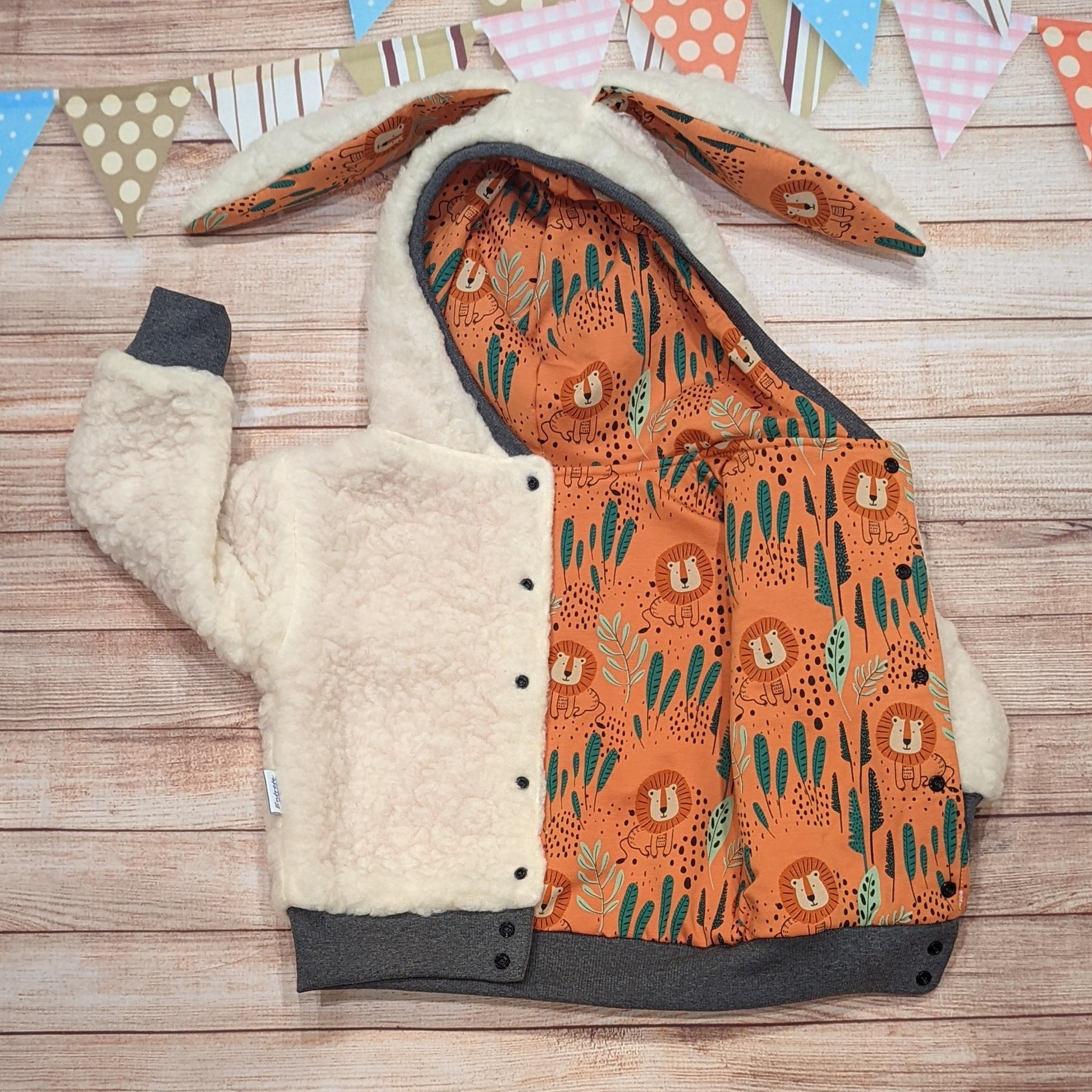 The gorgeous sherpa and orange lions reversible bunny hoodie. Handmade using sherpa fur, graphite ribbing and orange lions cotton French terry. Featuring front poppers and adorable bunny ears on the hood. Shown with poppers open, showing the orange lions reverse side.