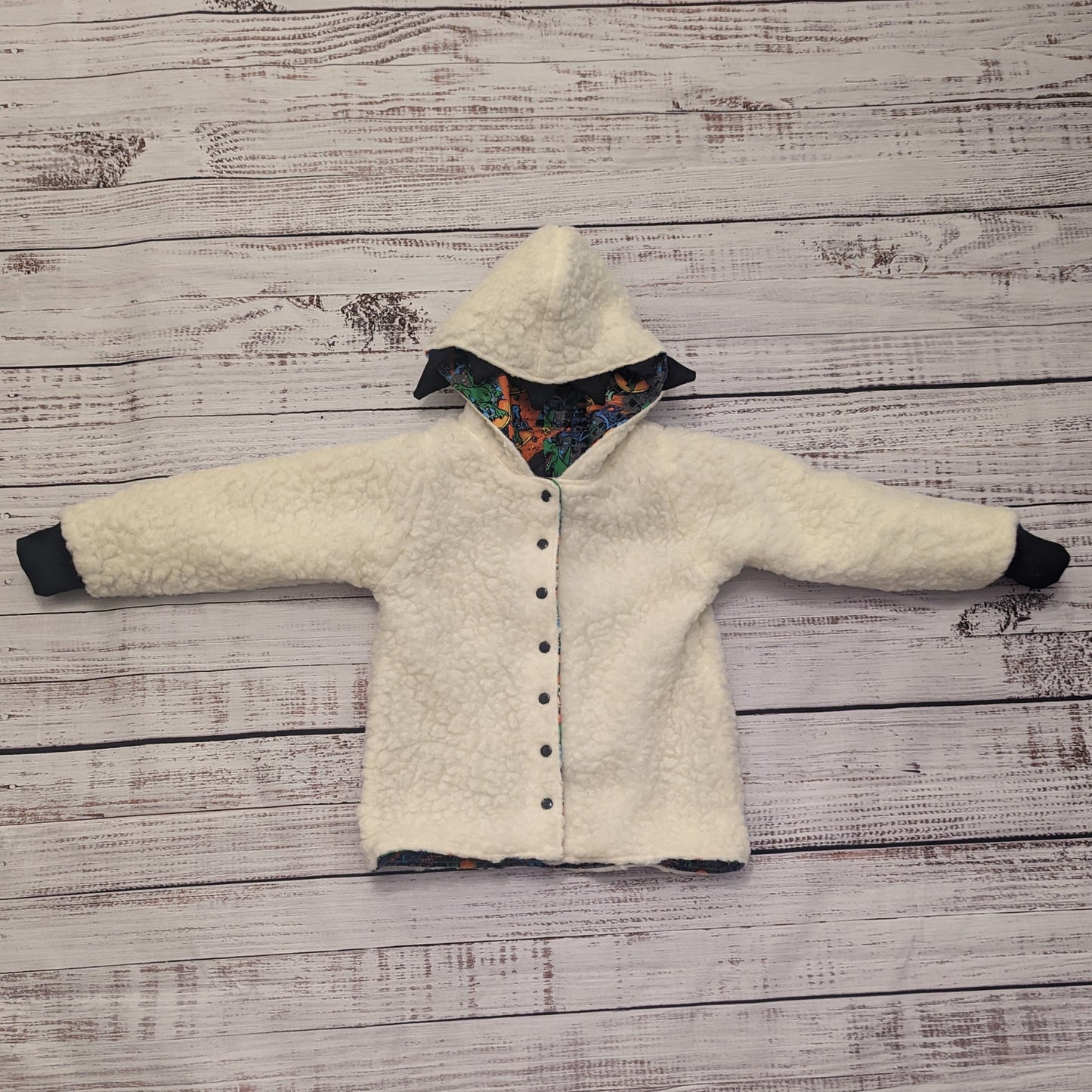 The ferociously cool street Dino reversible coat, shown with dinosaur teeth and spines for added fun. Handmade using street dino cotton French terry, black cotton ribbing and sherpa fur. Showing the reverse as a sherpa fur hoodie.