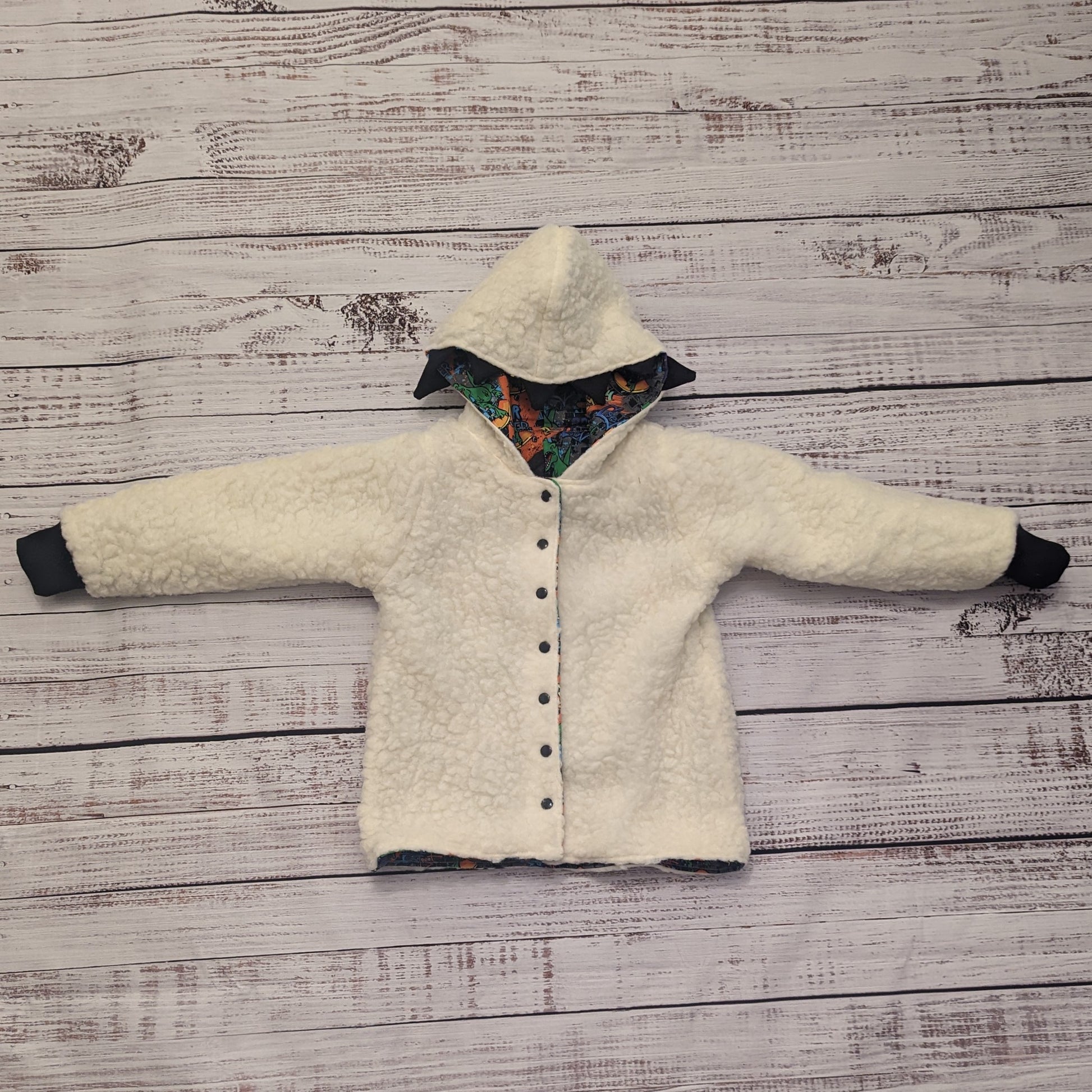 The ferociously cool street Dino reversible coat, shown with dinosaur teeth and spines for added fun. Handmade using street dino cotton French terry, black cotton ribbing and sherpa fur. Showing the reverse as a sherpa fur hoodie.