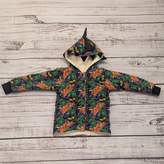 The ferociously cool street Dino reversible coat, shown with dinosaur teeth and spines for added fun. Handmade using street dino cotton French terry, black cotton ribbing and sherpa fur.
