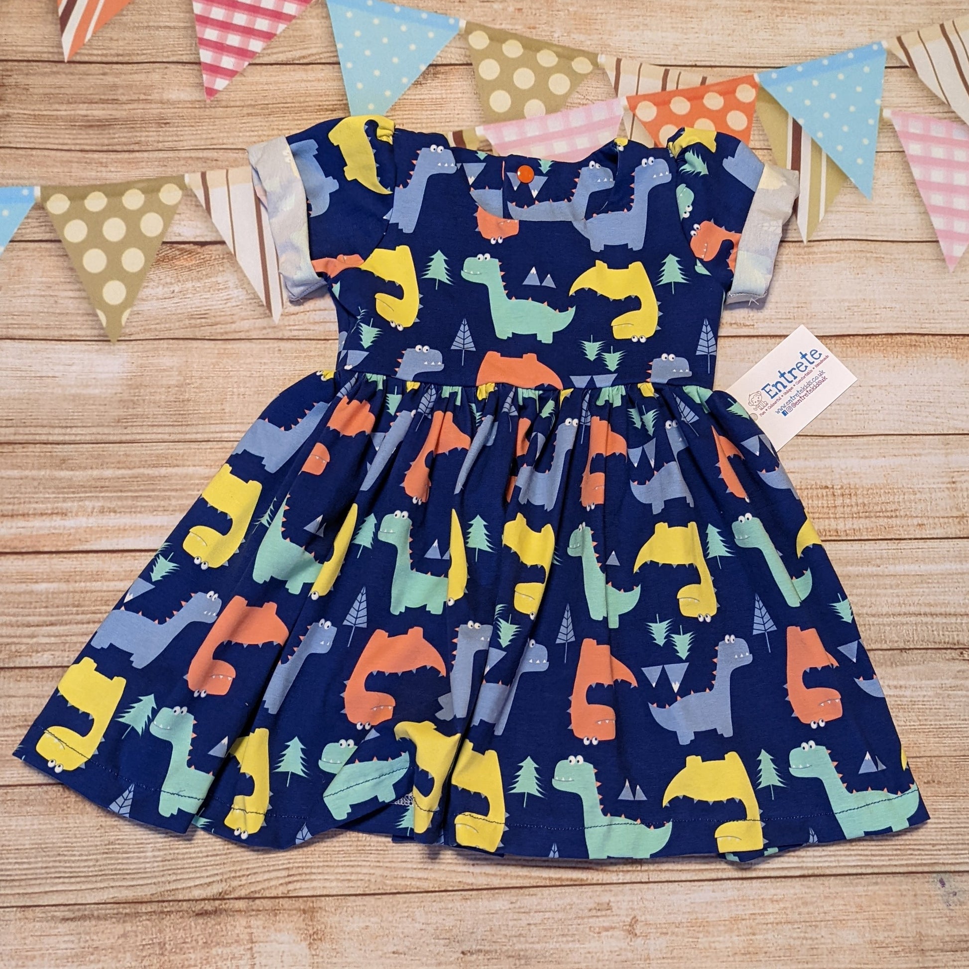 The short sleeved version of the colourful and fun blue dinosaur dress. Handmade using cotton jersey, featuring back poppers and rolled cuffs.