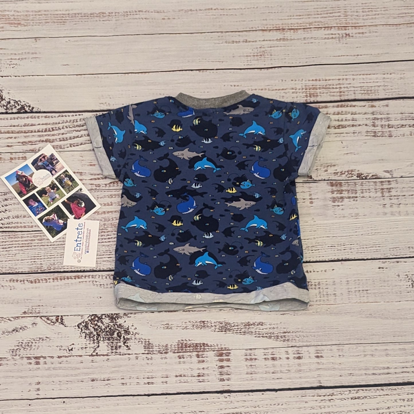 The short sleeved navy sea life shadows T-shirt. Handmade using navy sea life shadows cotton jersey and grey cotton ribbing. Shown from the rear.