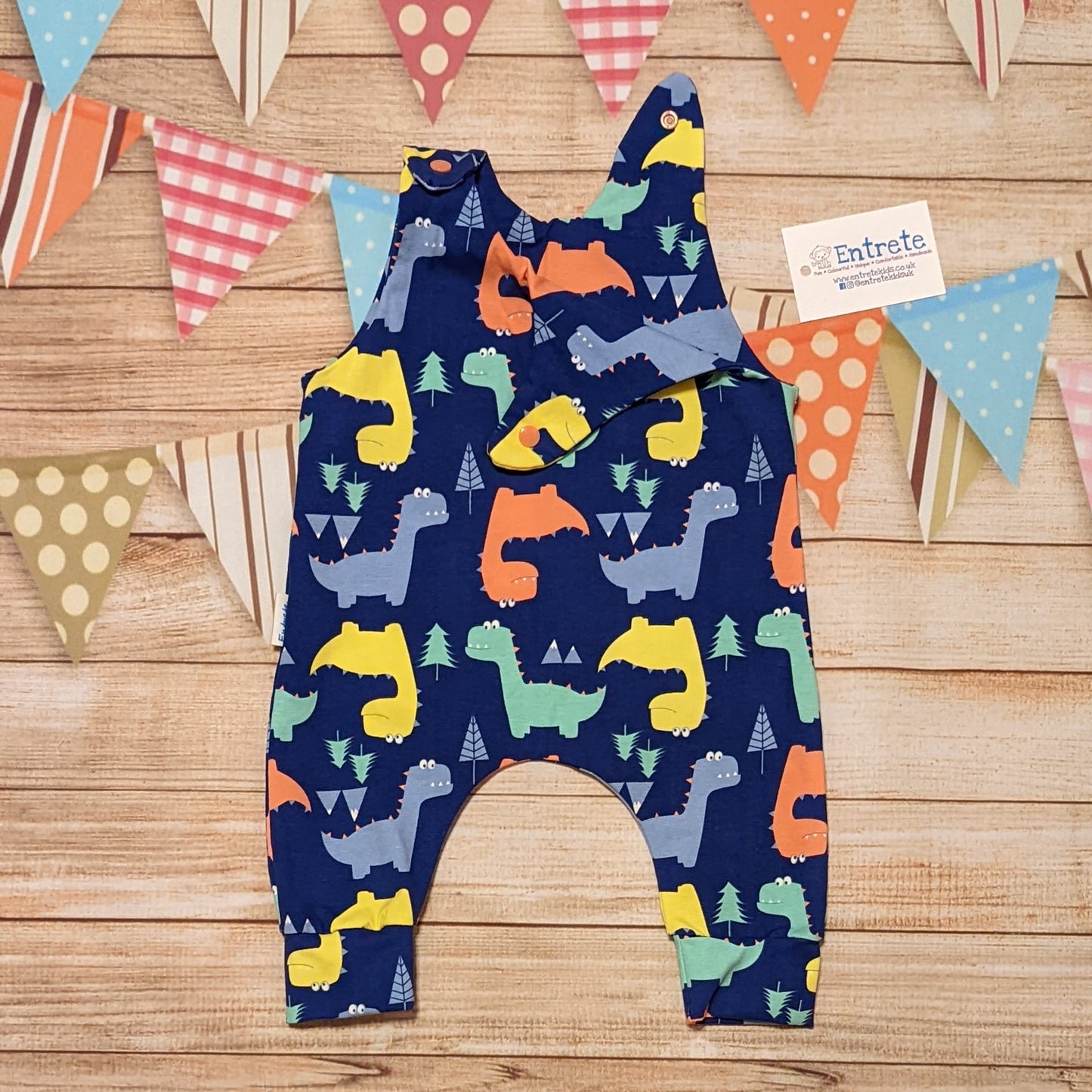 Colourful dinosaurs sleeveless romper, handmade using blue dinosaur cotton jersey. Shown with one shoulder popper open.