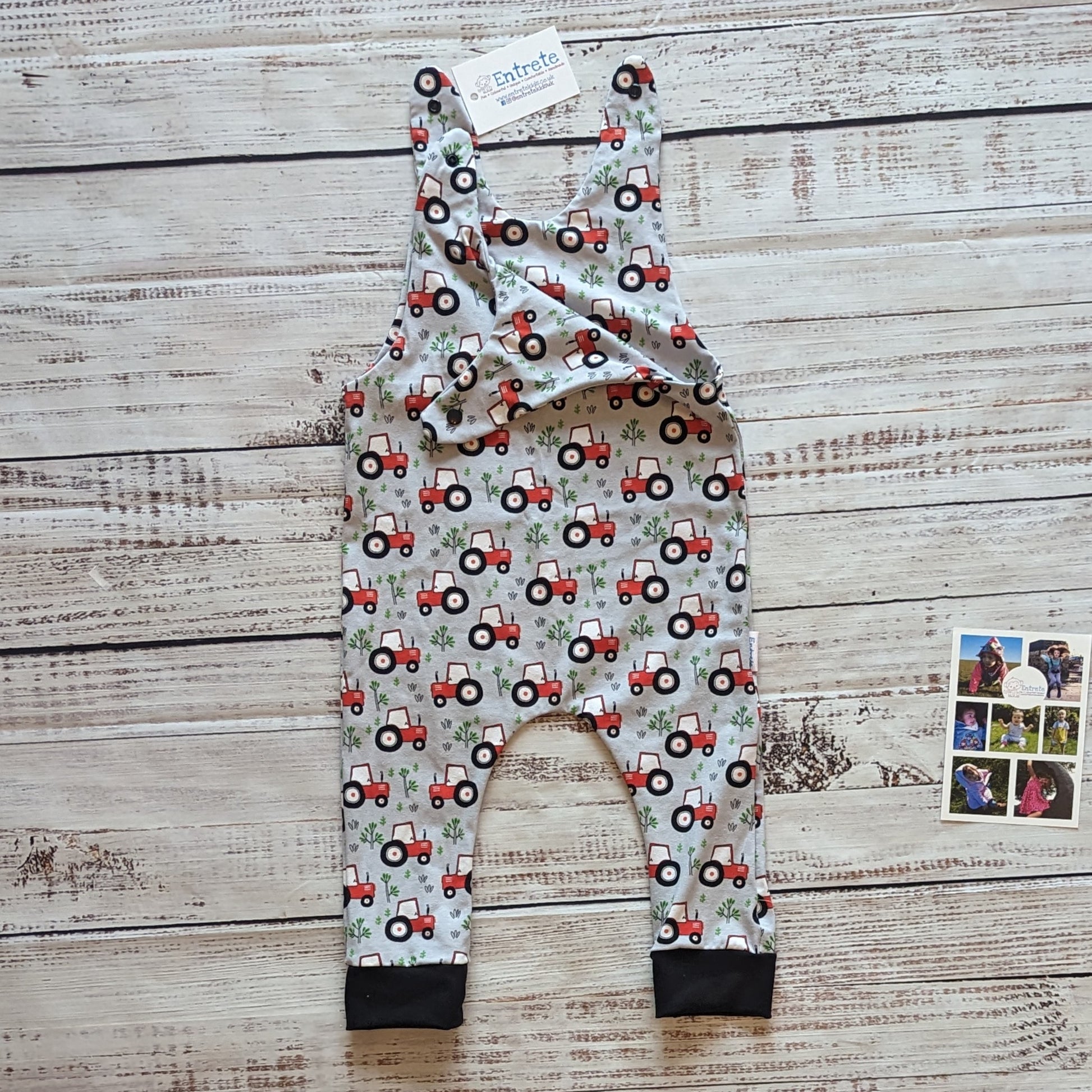 Fun red tractors on grey sleeveless romper. Handmade using grey tractors cotton jersey and black cotton ribbing. Shown with the shoulder entry open.