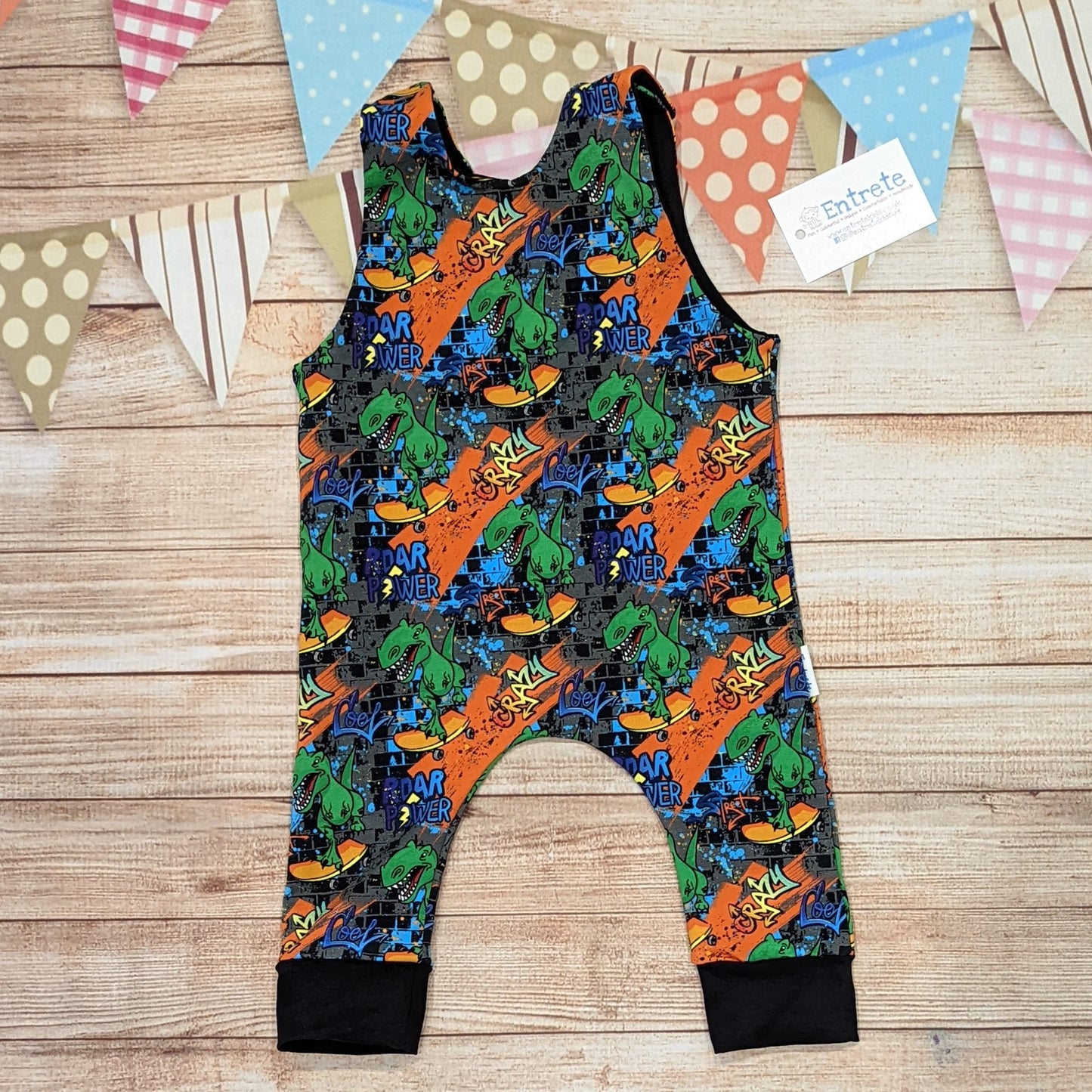 The insanely fun skateboarding dinosaurs romper. Handmade using street dino cotton French terry and black cotton jersey. Shown from the rear.