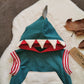 The fearsome teal shark hoodie. With sharks teeth and fin to the hood and a contrasting front pocket. Handmade using teal, white and grey cotton sweatshirt fleeces, red cotton jersey and red striped cotton ribbing. Close up of the hood.