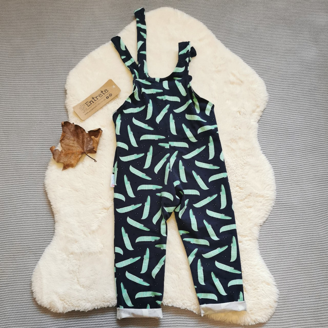 Rear of the amazingly fun navy crocodiles tie strap dungarees, handmade using navy crocodiles cotton jersey. Featuring a front pocket, rolled ankles and adjustable tie straps.