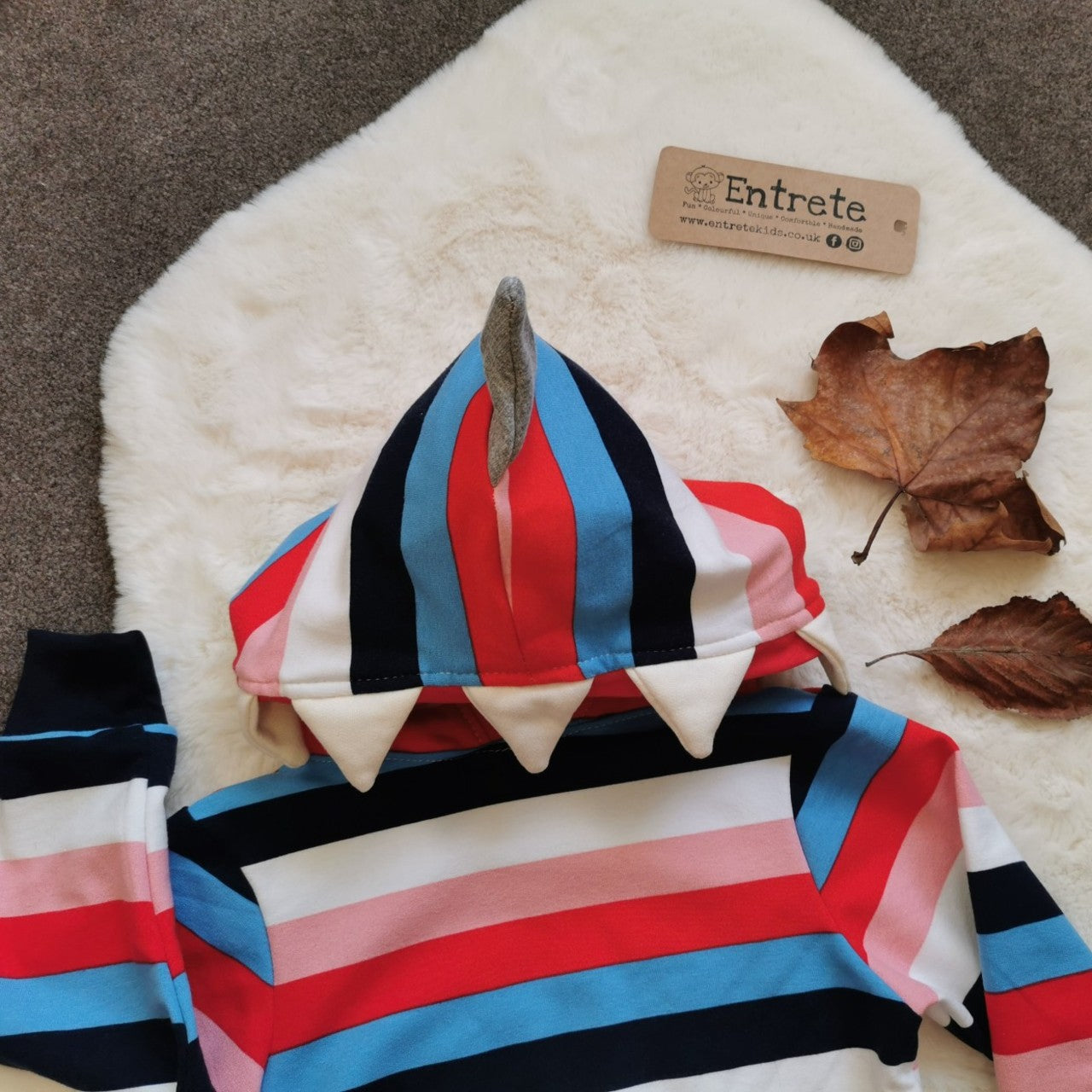 The colourful and fun colour striped shark hoodie. With shark teeth and fin on the hood, with the lining designed to look like the inside of a mouth. Handmade using colour striped cotton French terry, red cotton jersey, grey and white sweatshirt fleece and black cotton ribbing. Showing a close up of the hood.