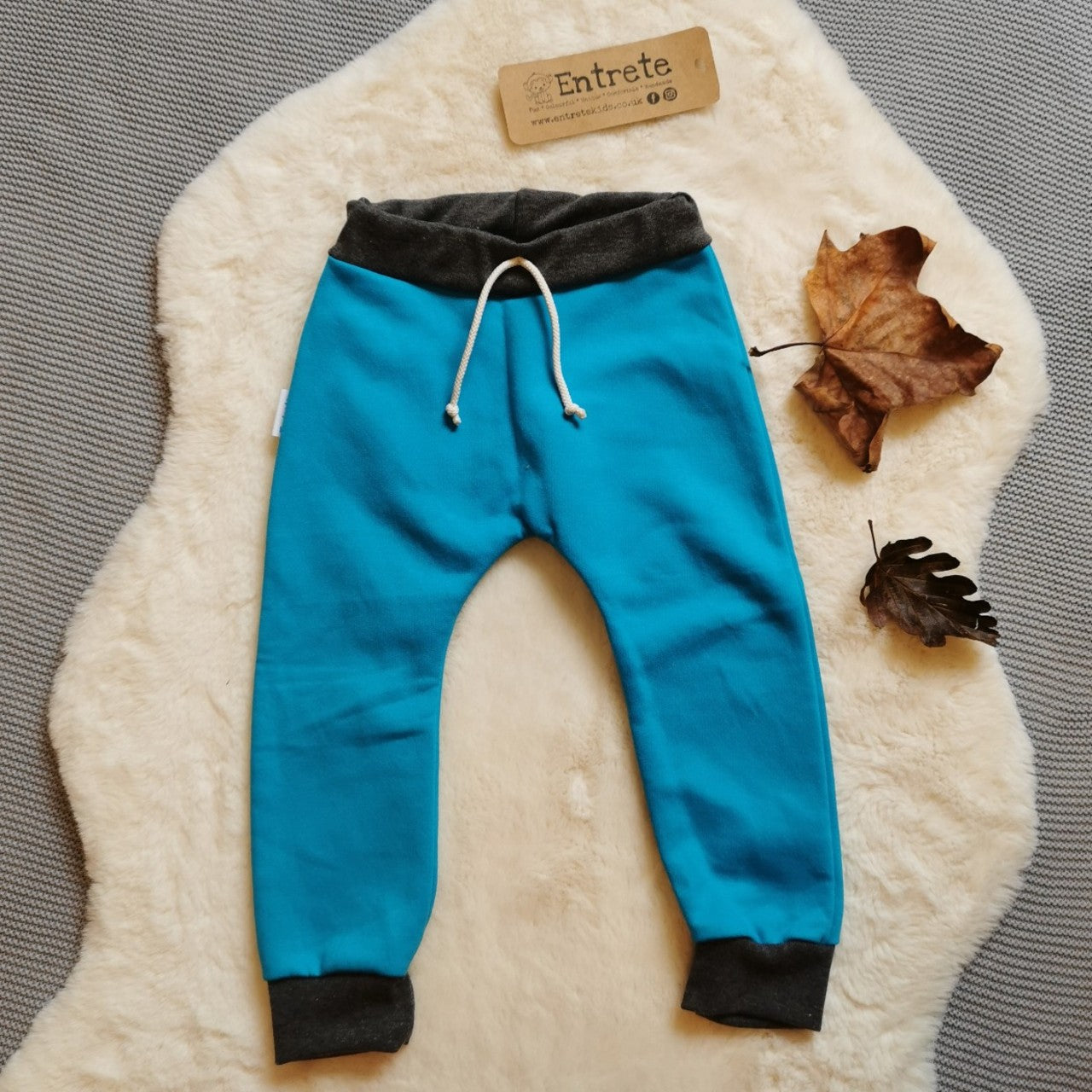 Harem joggers with elasticated waist, dropped crotch and roll-able ankle cuffs. Handmade using warm and vibrant sky blue cotton sweatshirt fleece, graphite ribbing and rainbow striped cotton jersey for the pocket.
