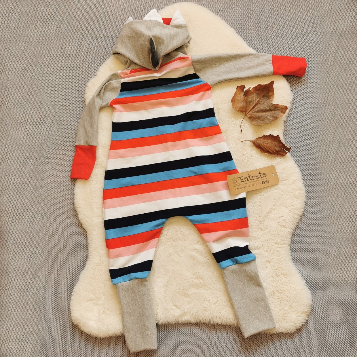 Rear view of The warm, colourful and fun colour striped shark animal romper. Handmade using colour striped cotton french terry, grey cotton sweat fabric and red cotton jersey.